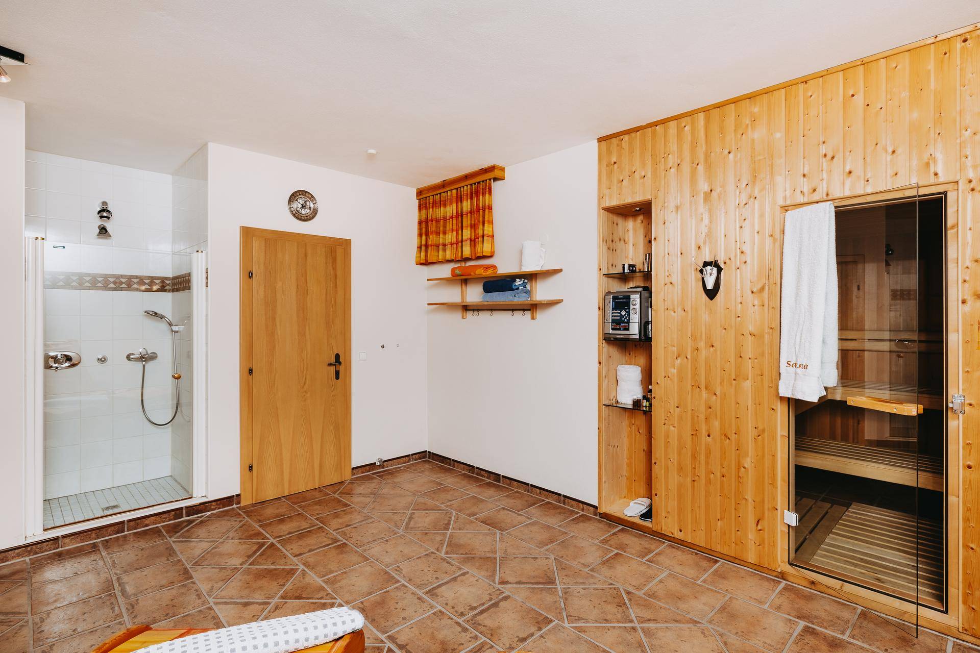 Wellnessbereich mit Sauna, Dusche und Fliesenboden, ideal zur Entspannung.