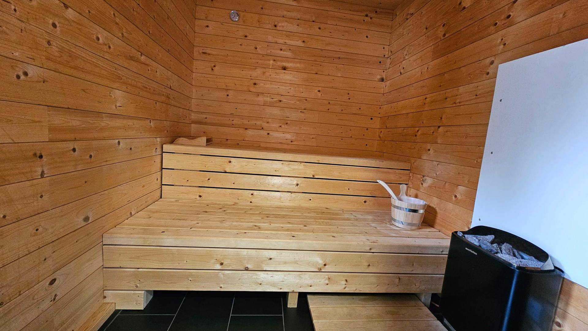 Traditionelle Holzsauna mit Bänken und Saunaofen für entspannende Momente.