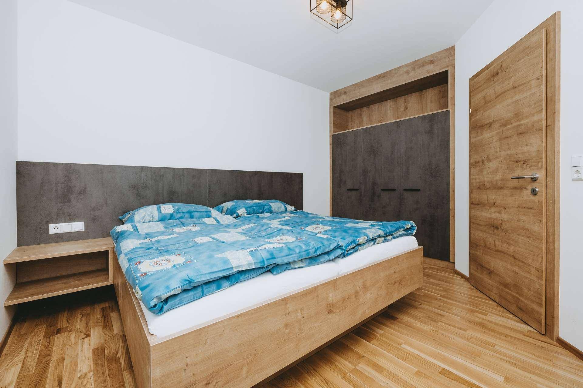 Gemütliches Schlafzimmer mit Holzbett, integrierten Nachttischen und Einbauschrank.