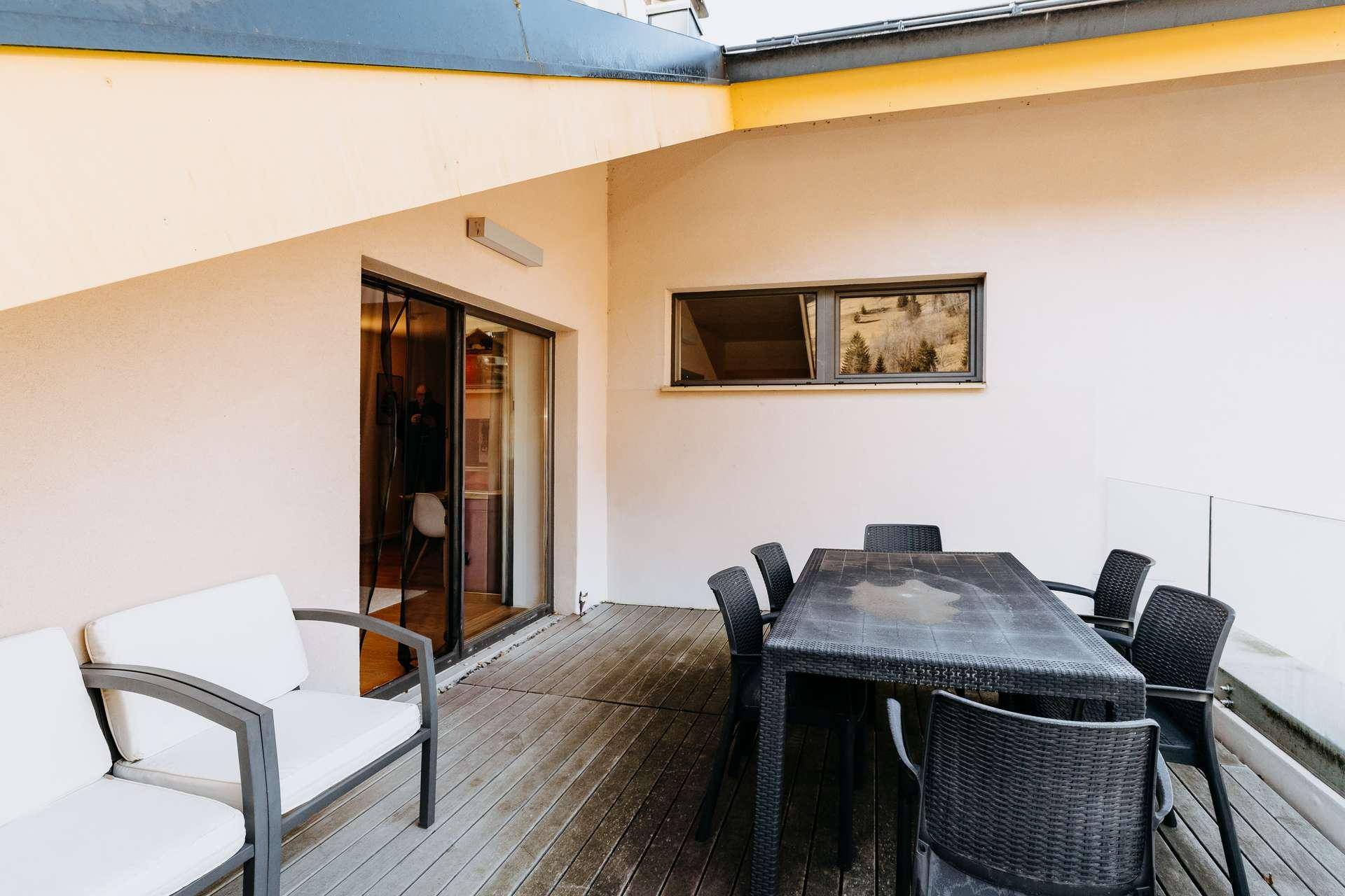 Geräumige Terrasse mit Esstisch und Sitzgelegenheiten, umgeben von Natur.