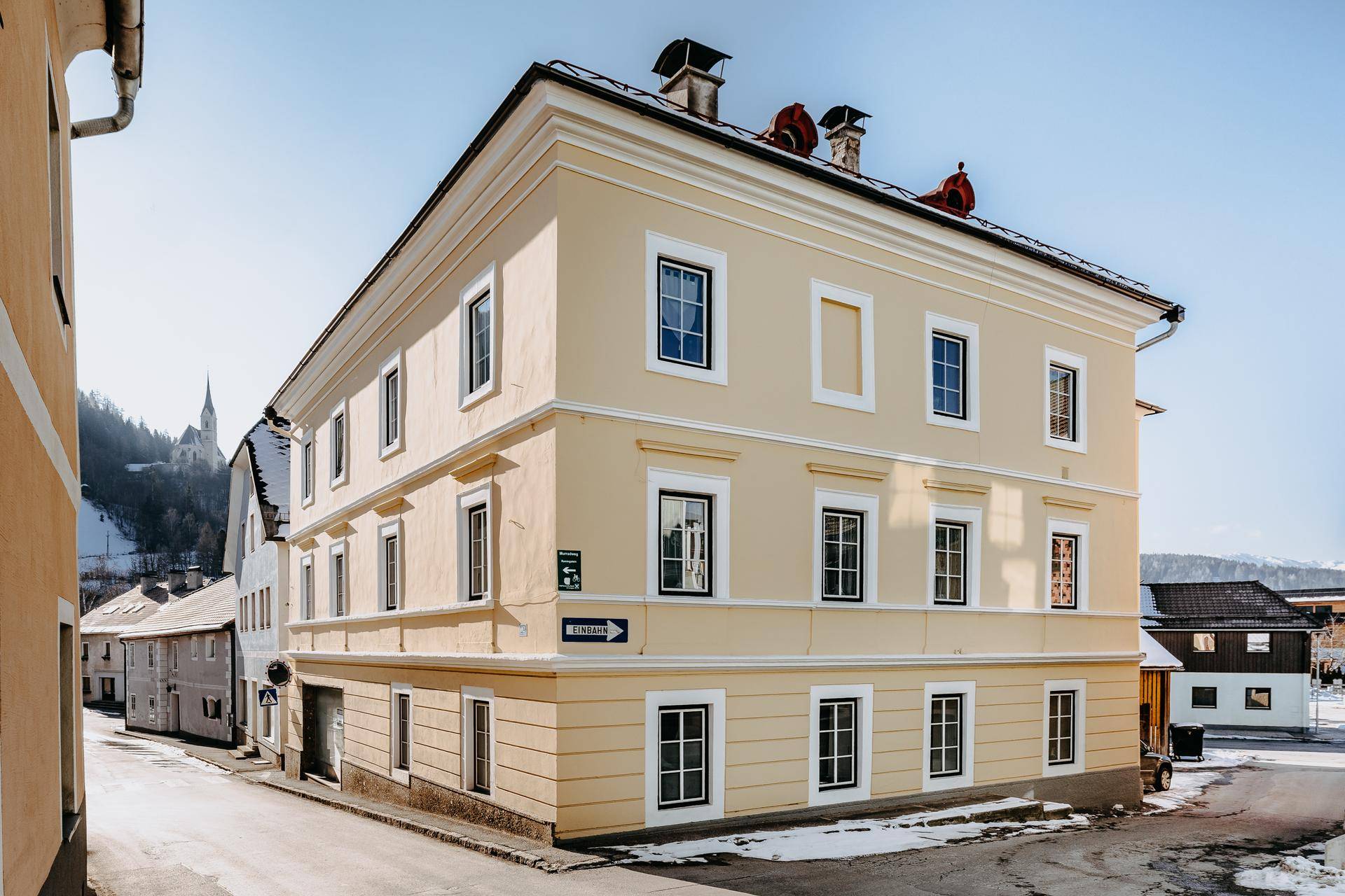 Historisches Gebäude mit gelber Fassade und traditionellen Fenstern in einer verschneiten Stadtansicht.