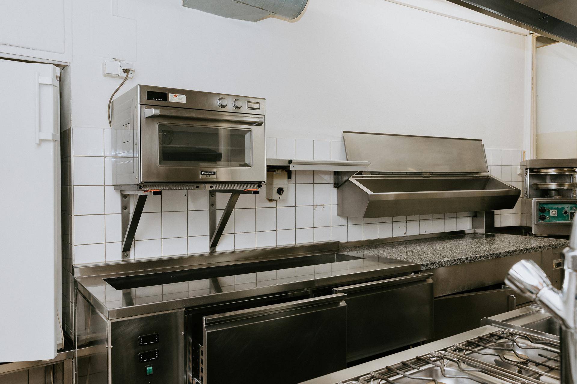 Professionelle Edelstahlküche mit Backofen, Kochfeld und Arbeitsflächen für den Restaurantbetrieb.