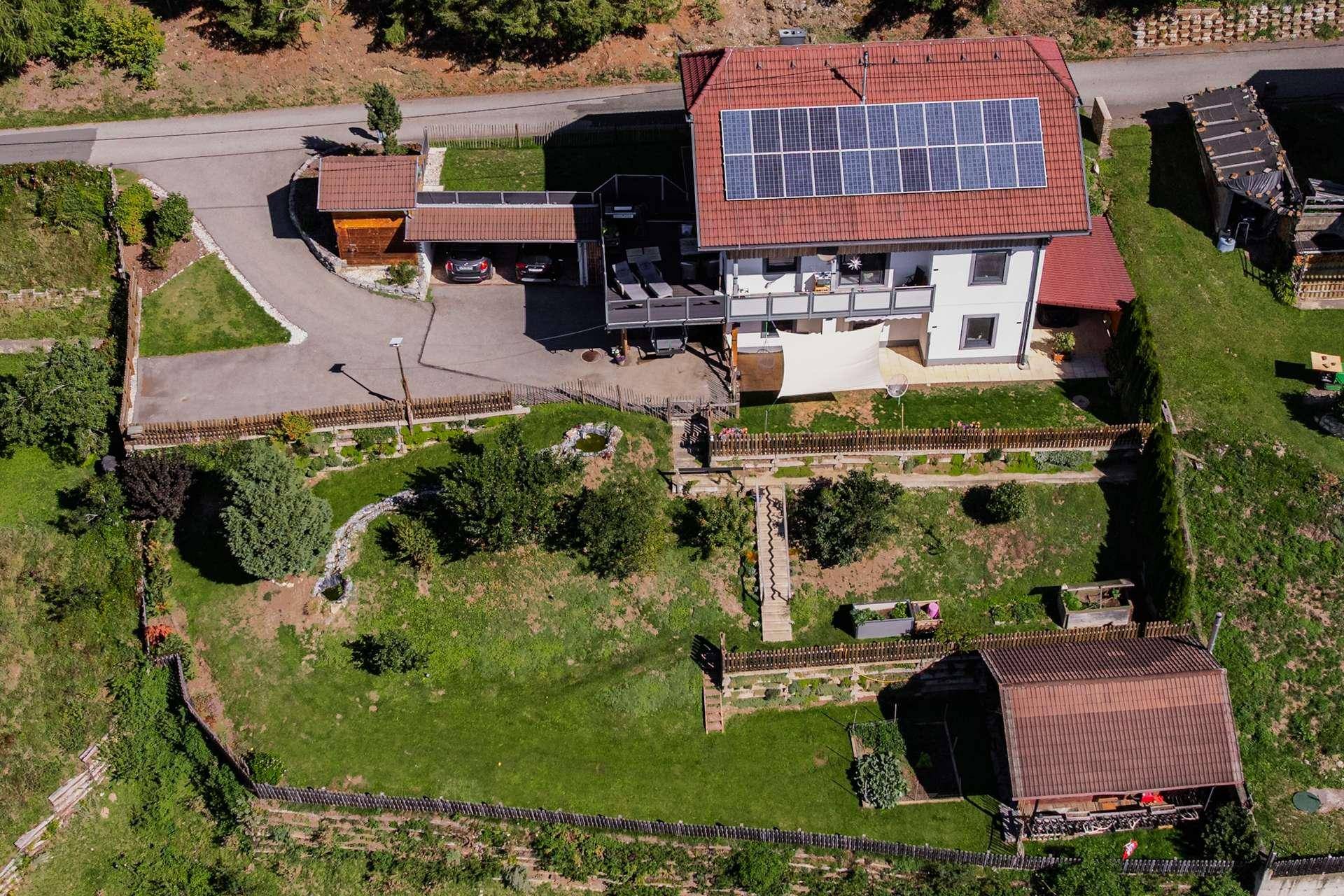 Vogelperspektive des Hauses mit Solaranlage, Terrasse, weitläufigem Garten und Zufahrt.