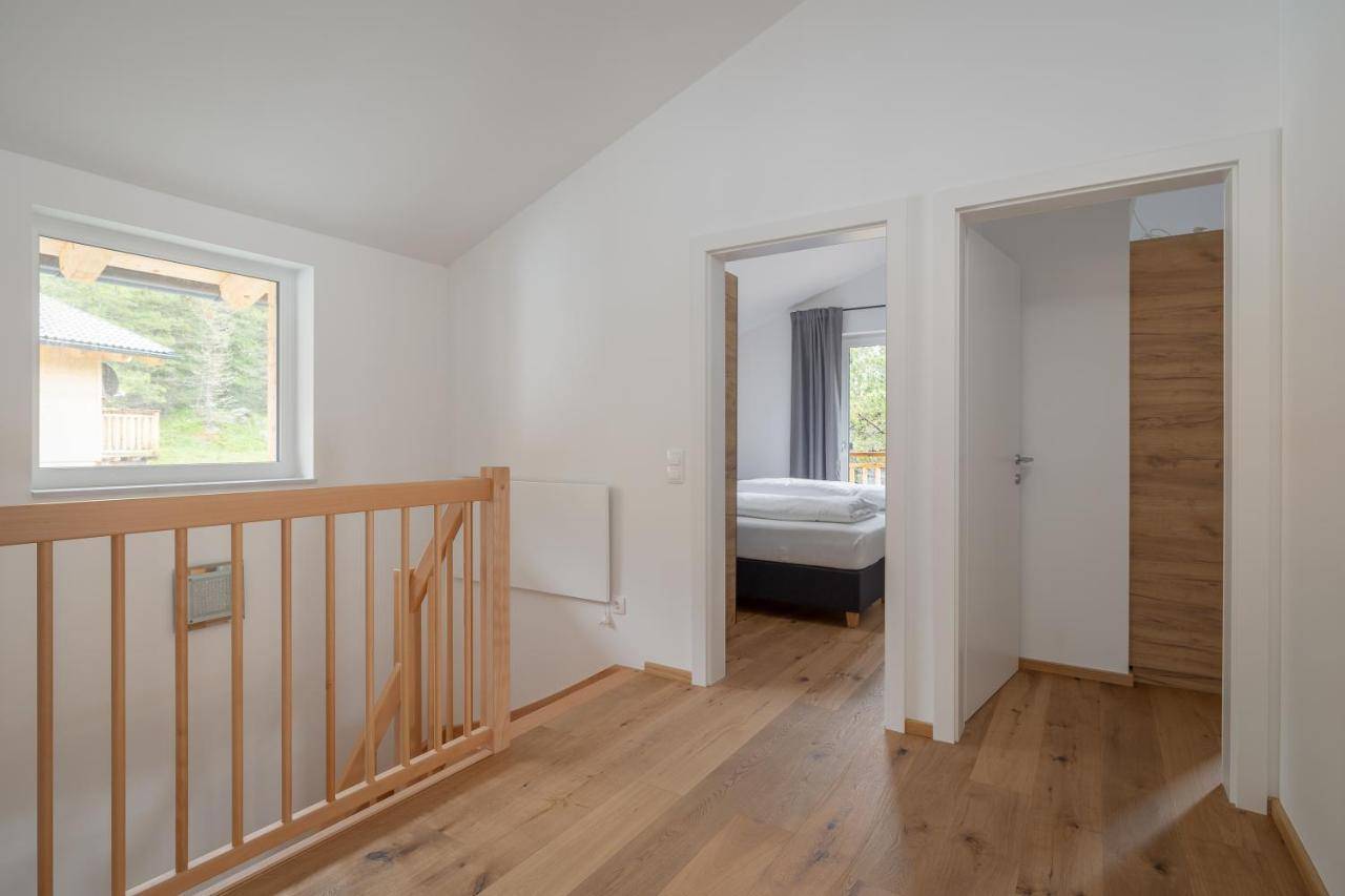 Heller Flur im Obergeschoss mit Holztreppe, Parkettboden und Blick ins Schlafzimmer.