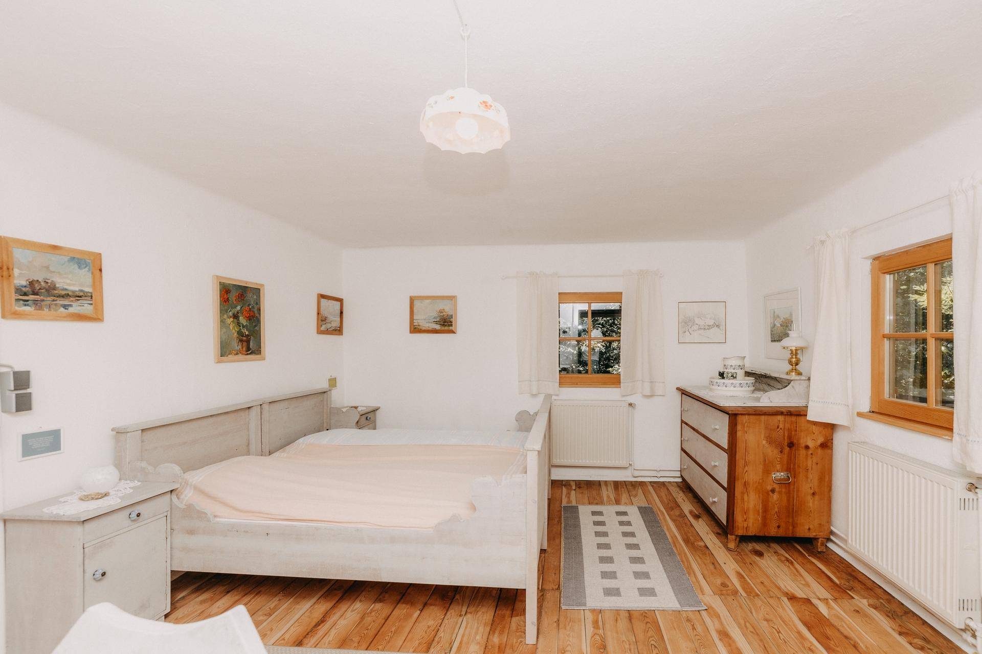 Geräumiges Schlafzimmer mit zwei Einzelbetten, Holzboden und Kommode.