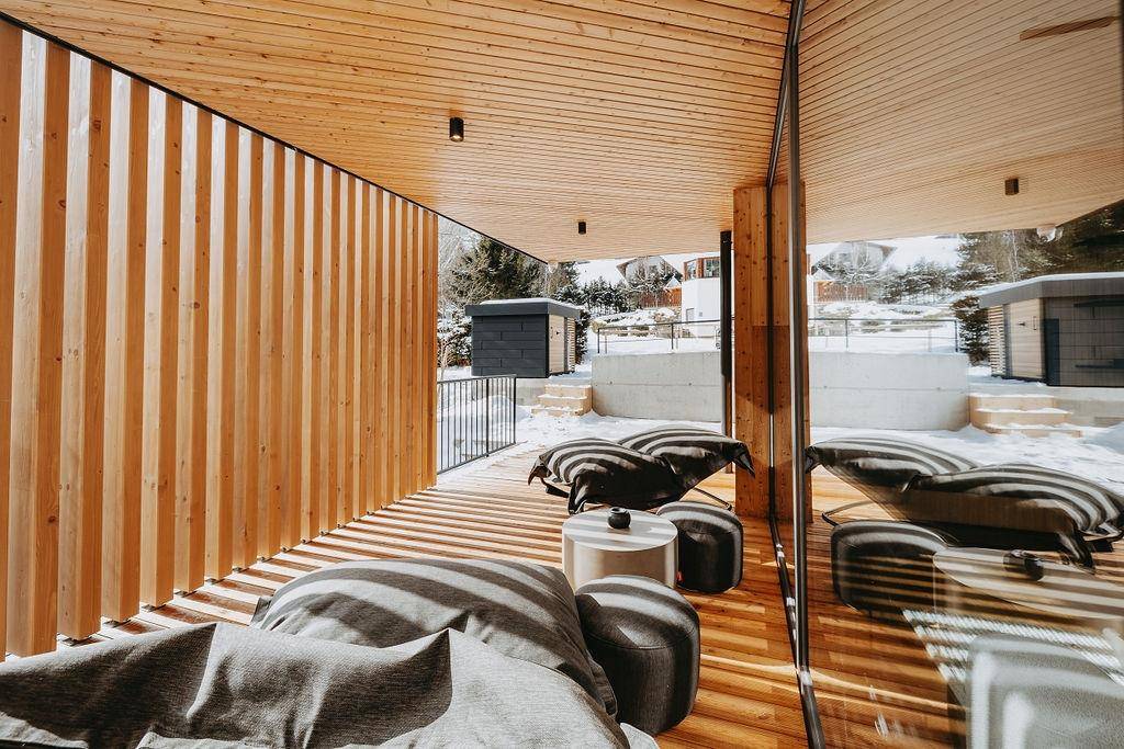 Überdachte Holzterrasse mit bequemen Sitzsäcken und Blick auf die verschneite Umgebung.