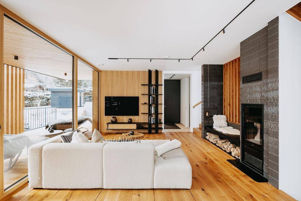 Helles Wohnzimmer mit großem Sofa, Holzboden und Blick auf die verschneite Außenanlage.
