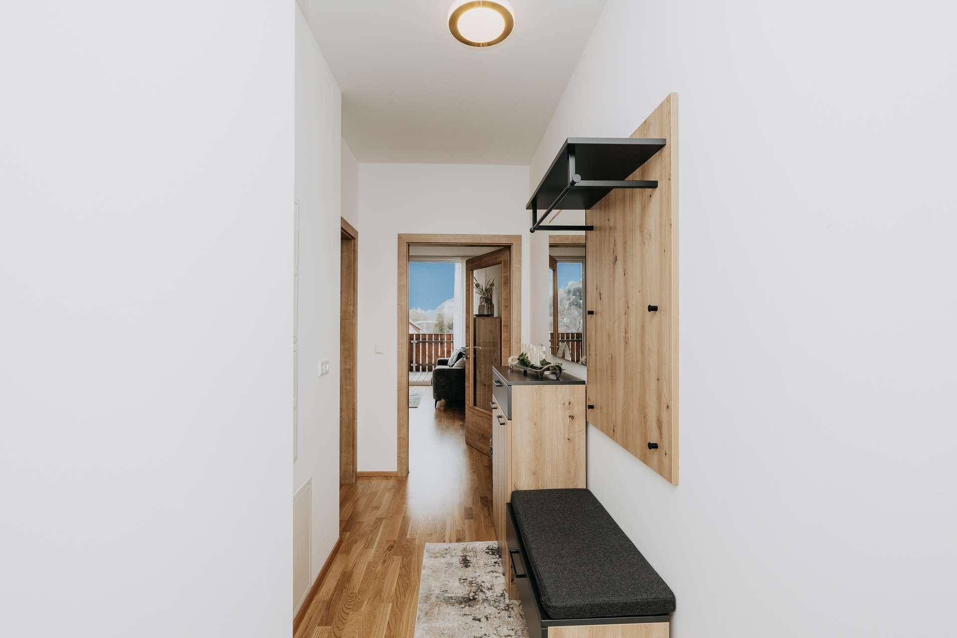 Heller Eingangsbereich mit Holzfußboden und moderner Garderobe, die zu den Wohnräumen führt.