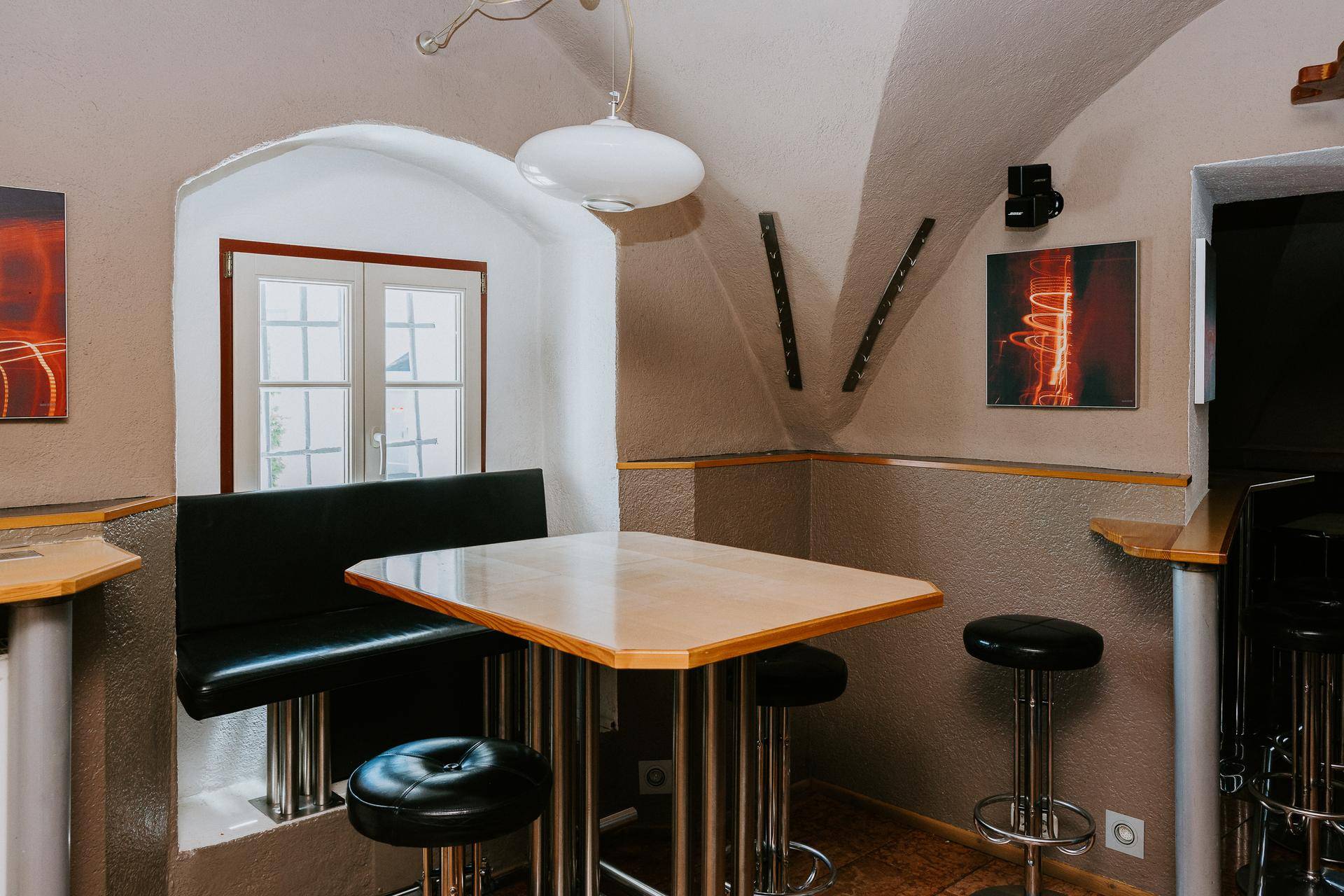 Gemütlicher Sitzbereich im Keller mit gewölbter Decke, Holztischen und Bänken.