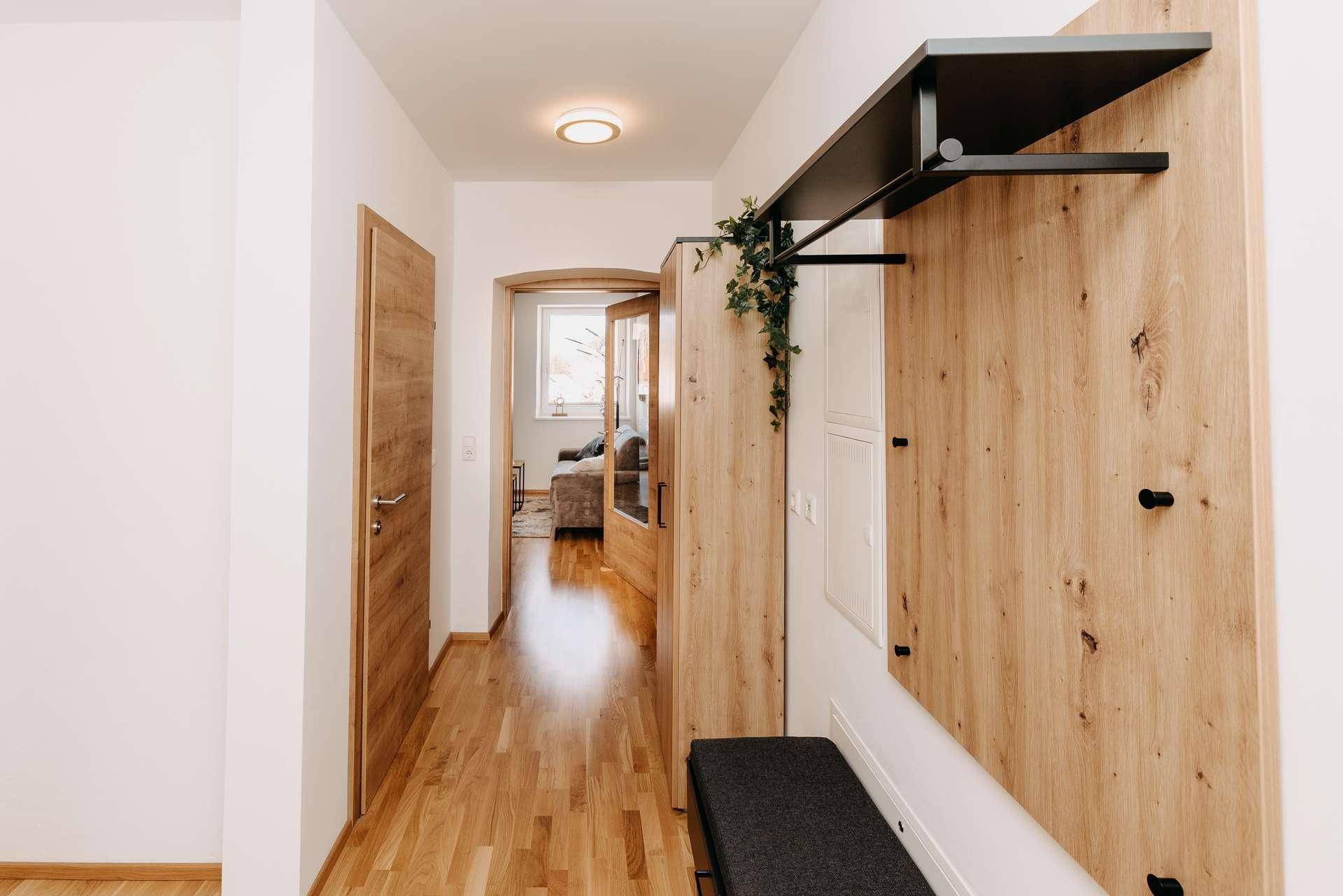 Eingangsbereich mit Garderobe, Holzboden und Zugang zu den Wohnräumen.