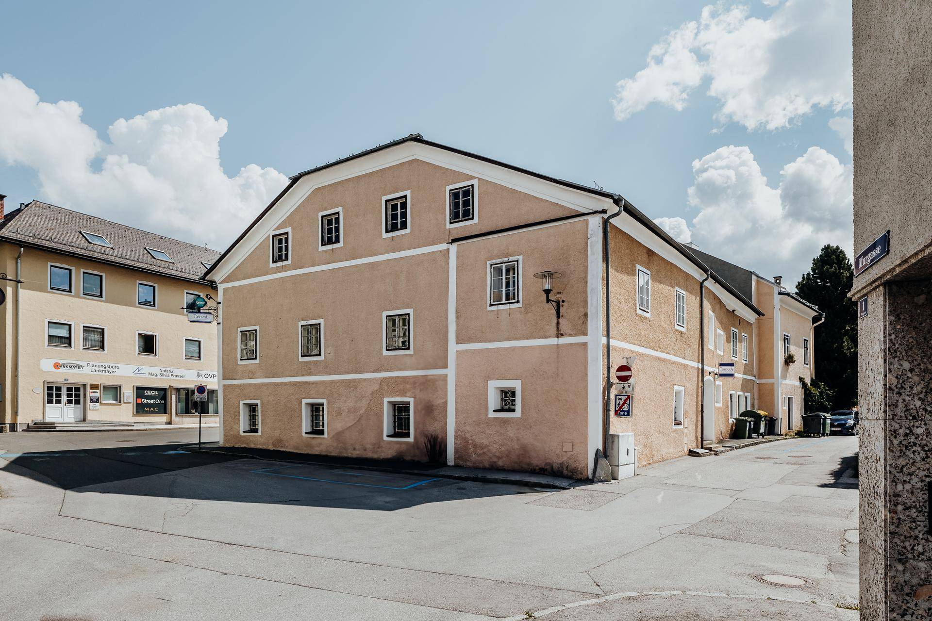 Seitenansicht des historischen Gebäudes mit mehreren Fenstern und angrenzender Straße.