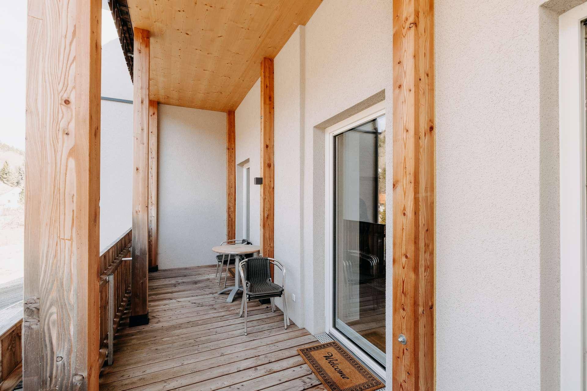 Geräumiger Holzbalkon mit Sitzgelegenheiten und Blick auf die umliegende Natur.