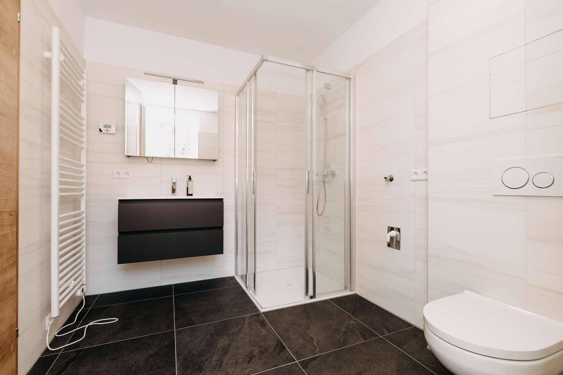 Modernes Badezimmer mit Duschkabine, Hänge-WC und beheiztem Handtuchhalter.