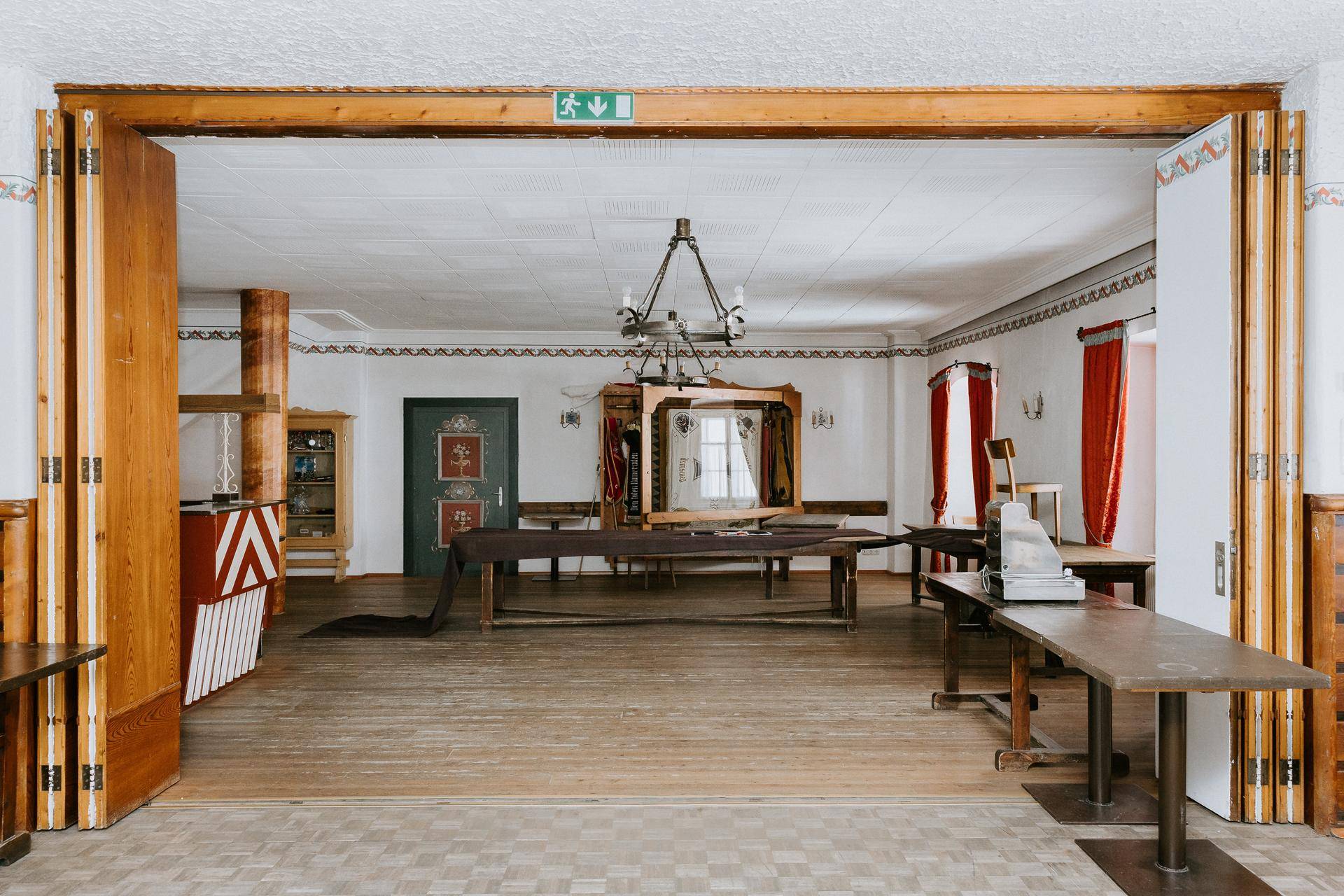 Großer Veranstaltungsraum mit Falttüren, traditioneller Deckenbeleuchtung und Vinylboden.