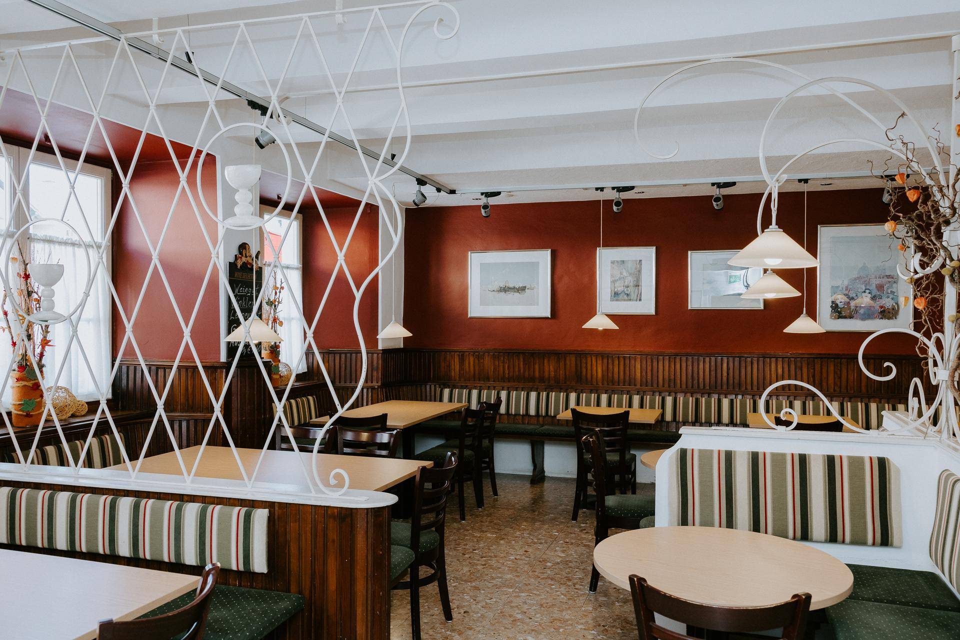 Gemütlicher Restaurantbereich mit roten Wänden, Holzbänken und traditionellen Tischen.