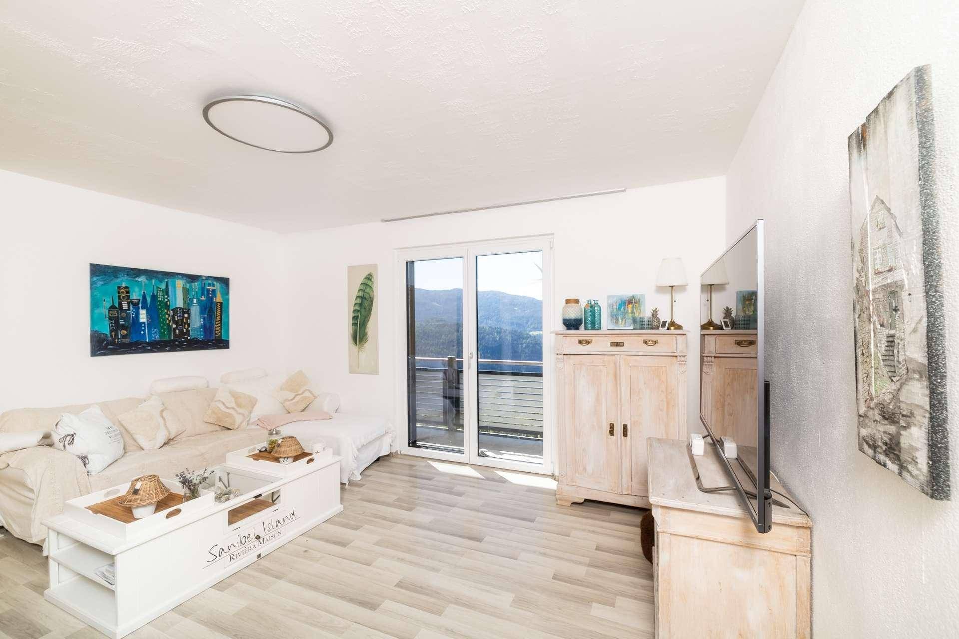 Helles Wohnzimmer mit bequemer Couch, moderner Dekoration und Balkonzugang.