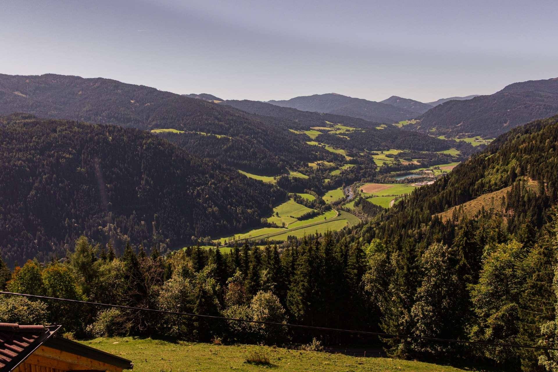 Malerischer Panoramablick über ein grünes Tal mit dichten Wäldern und sanften Hügeln.
