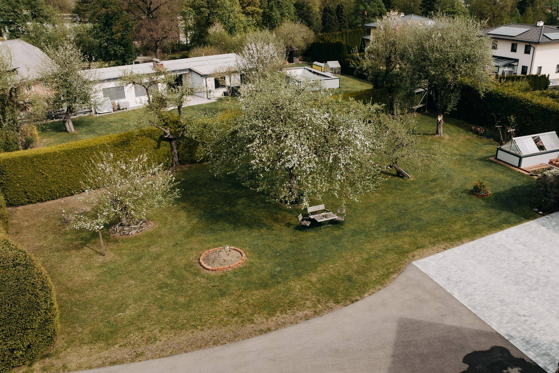 Weitläufiger Gartenbereich mit Obstbäumen, Rasenflächen und einer Hecke, ideal zum Entspannen.
