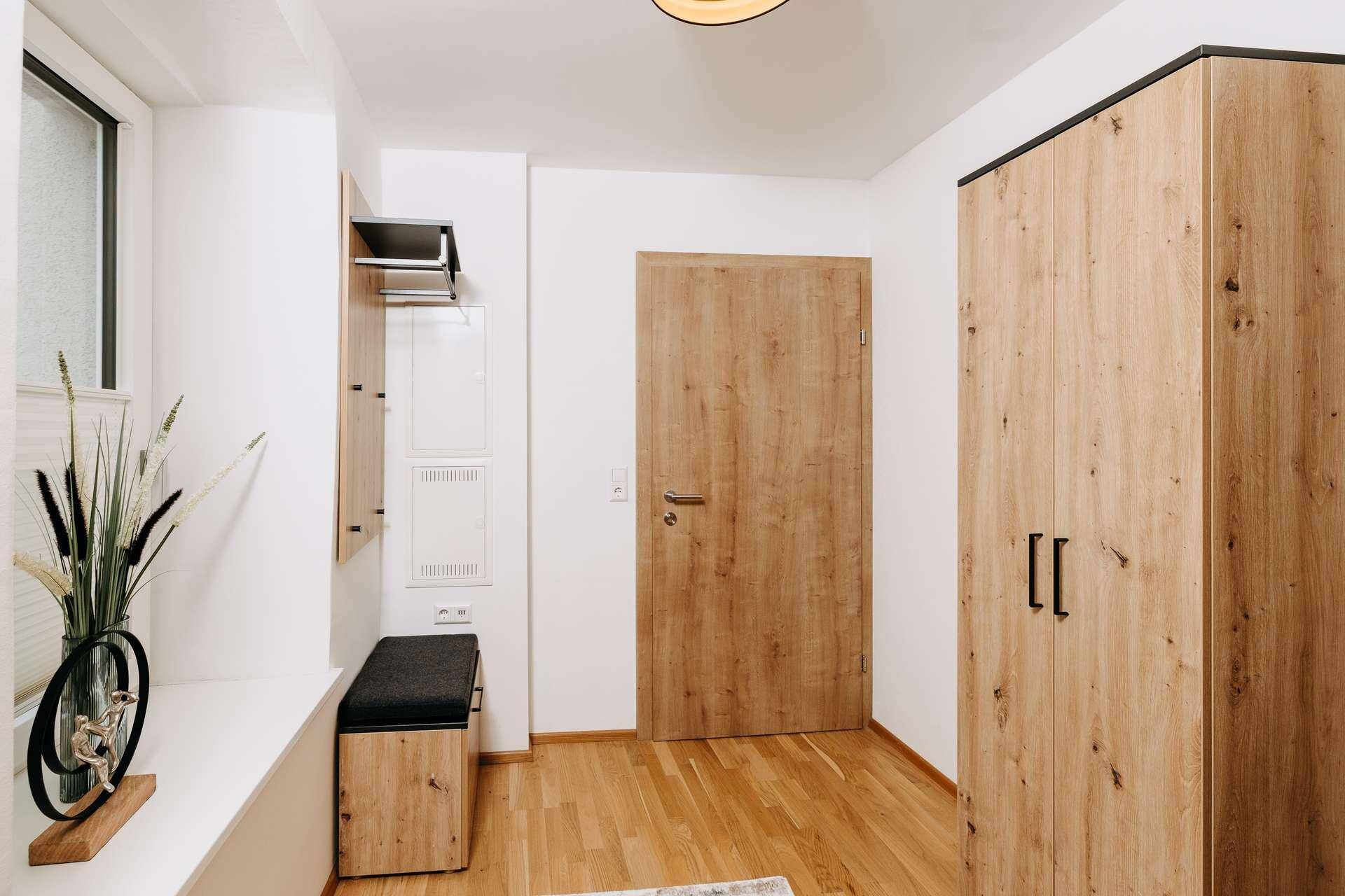 Heller Eingangsbereich mit Holzboden, Garderobe und moderner Holztür.