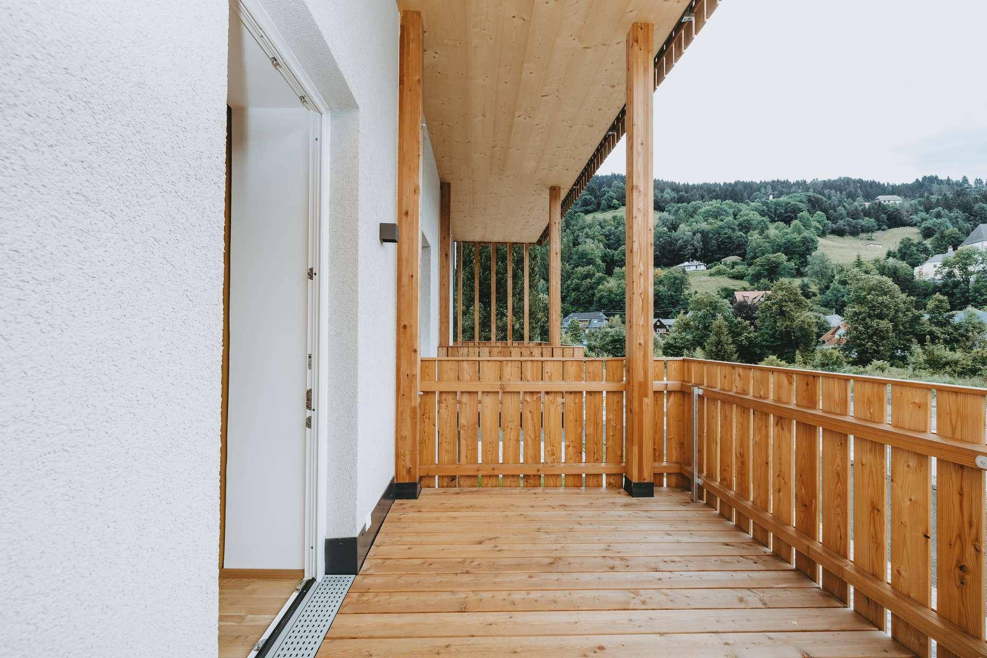 Geräumiger Holzbalkon mit Blick auf die grüne Hügellandschaft, ideal für Entspannung im Freien.