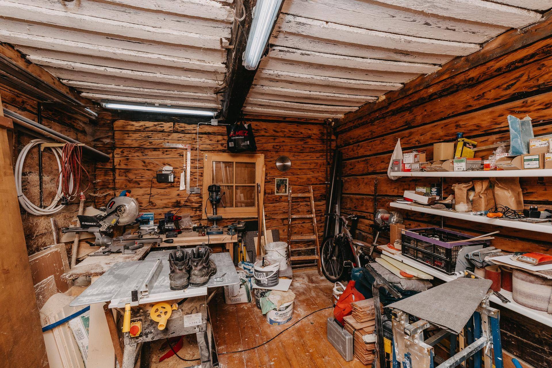 Rustikale Werkstatt mit Holzwänden, Werkbank und verschiedenen Werkzeugen für Handwerksarbeiten.