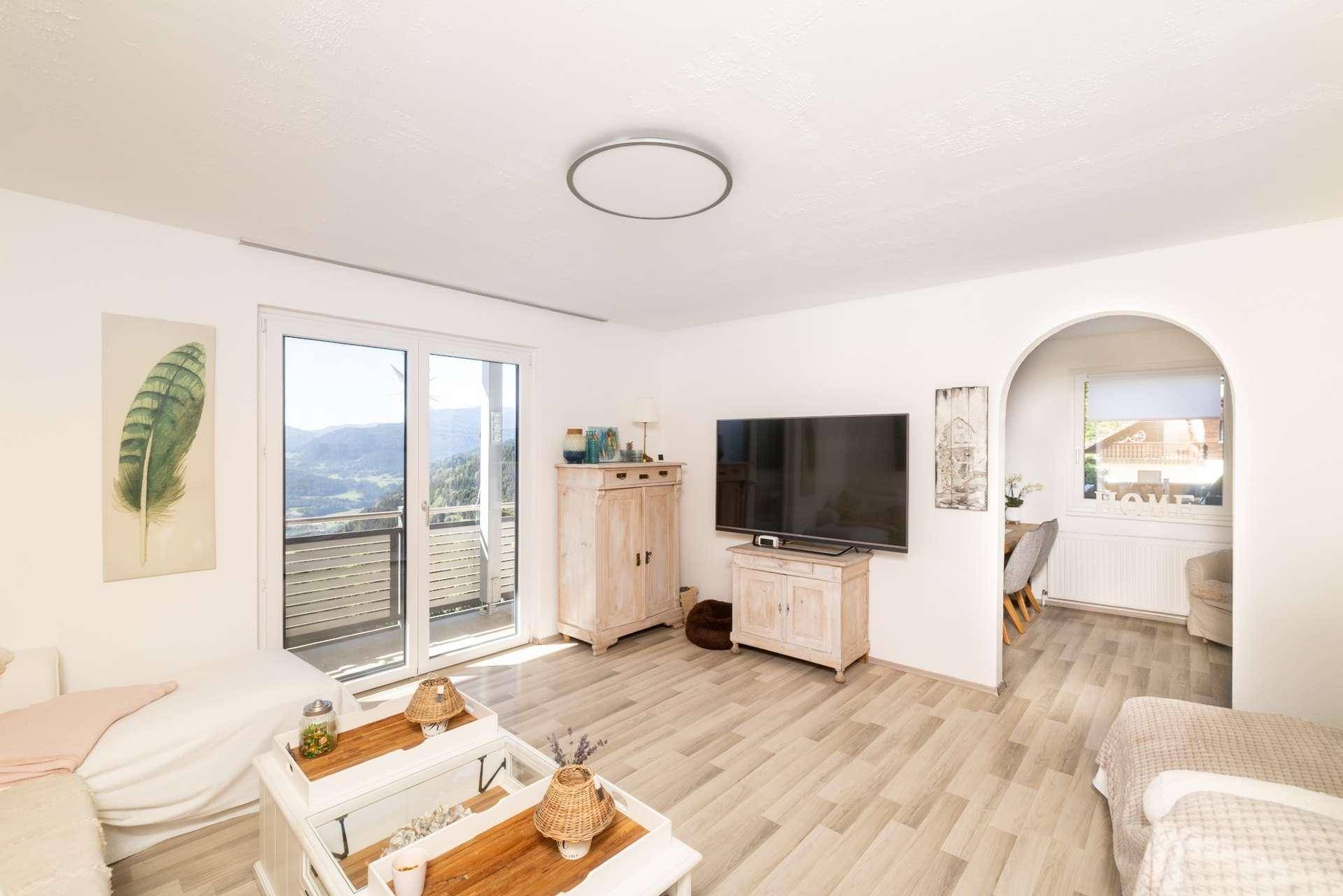 Gemütliches Wohnzimmer mit Sofa, Fernseher und direktem Zugang zu einem Balkon.