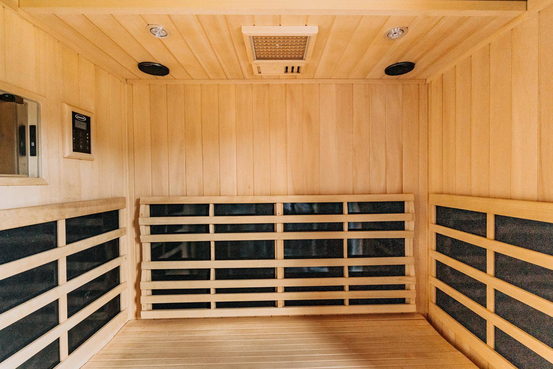 Holzvertäfelte Sauna mit Bänken und Infrarotstrahlern für Entspannung.