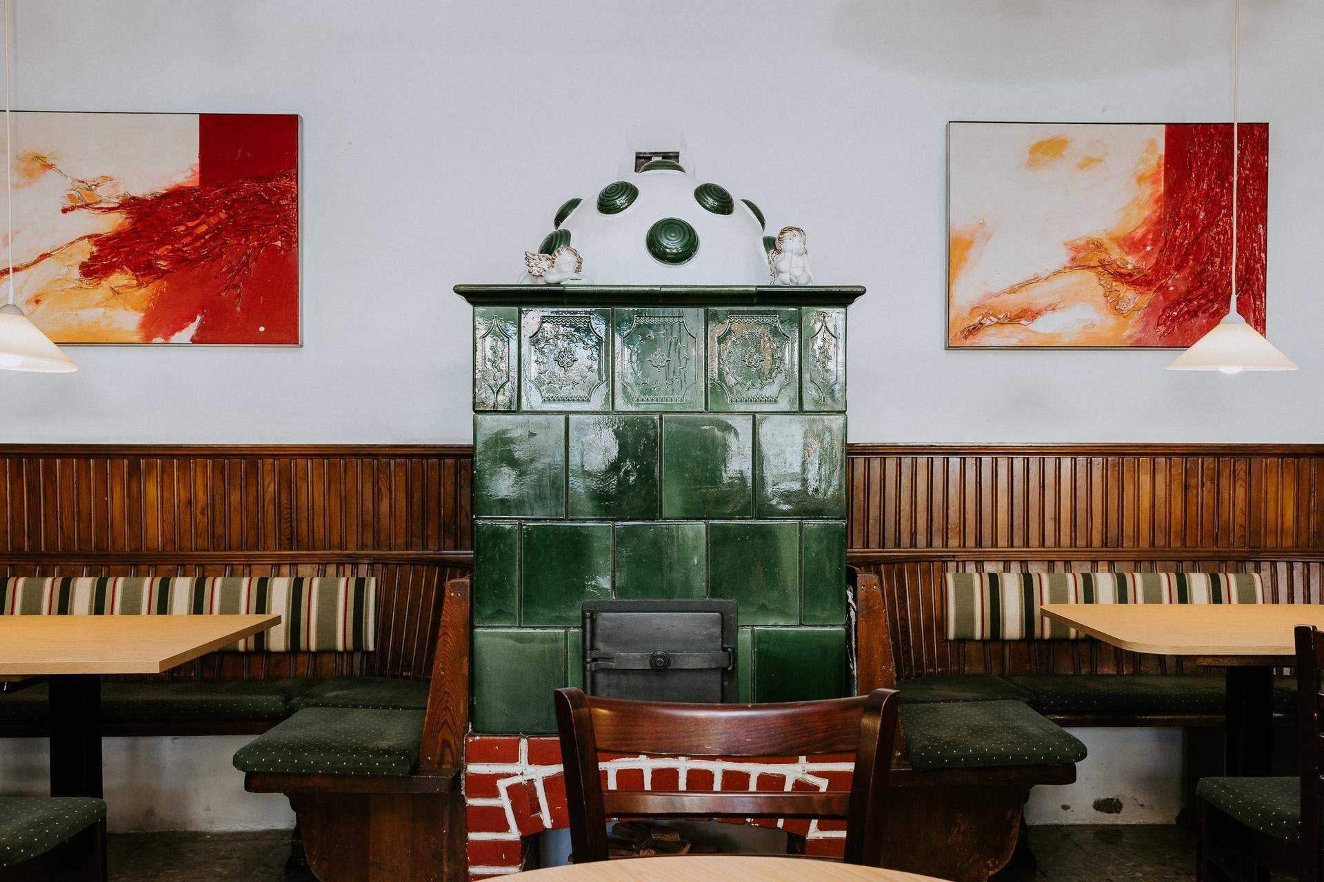Detailansicht des traditionellen grünen Kachelofens in einem gemütlichen Restaurantbereich.