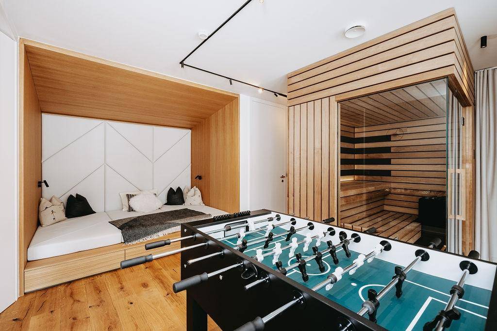Freizeitraum mit Tischfußball, integrierter Sauna und gemütlicher Liegefläche.