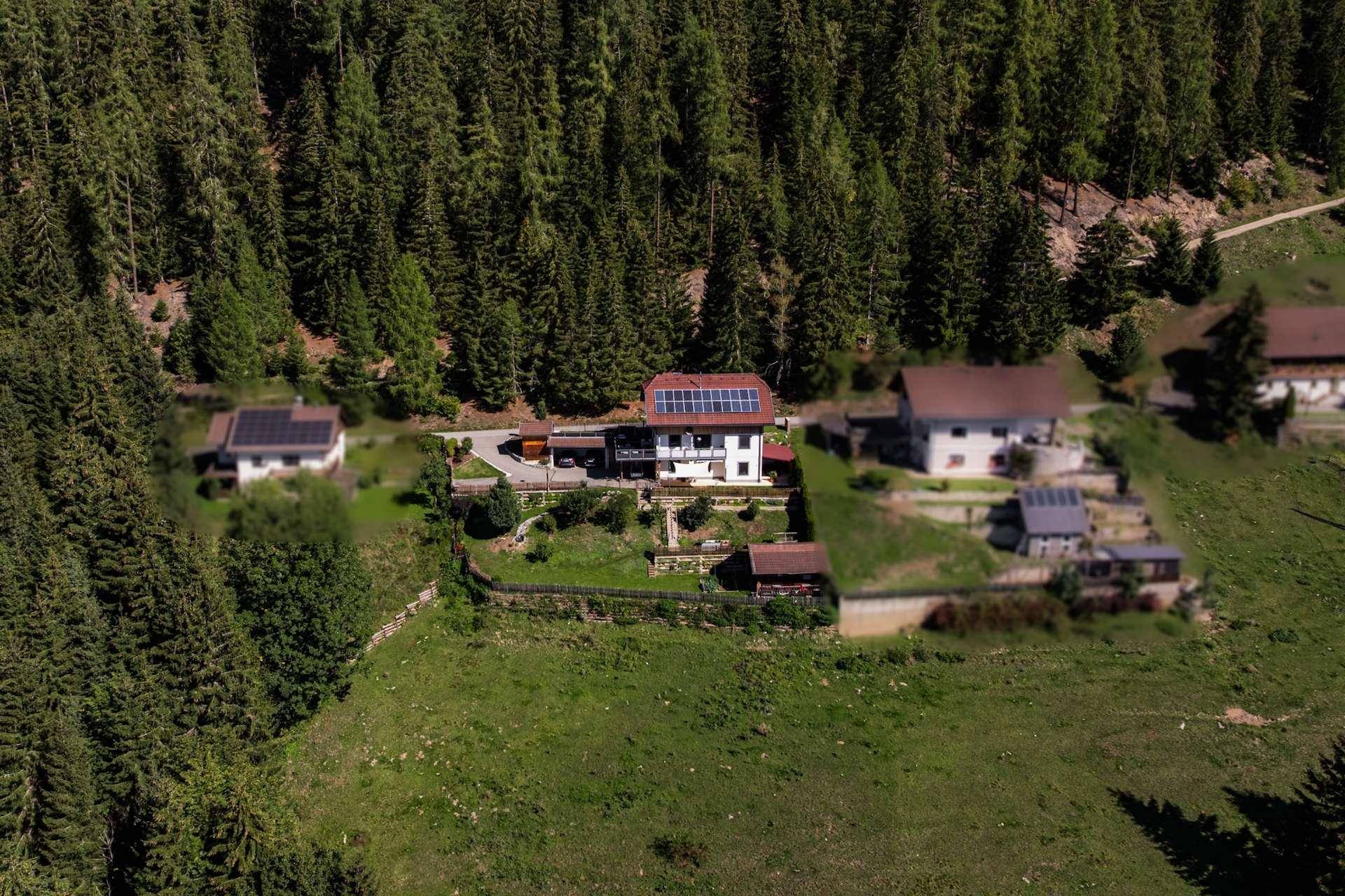 Panoramablick von oben auf das Anwesen mit Haus, Garten und der umliegenden Waldlandschaft.