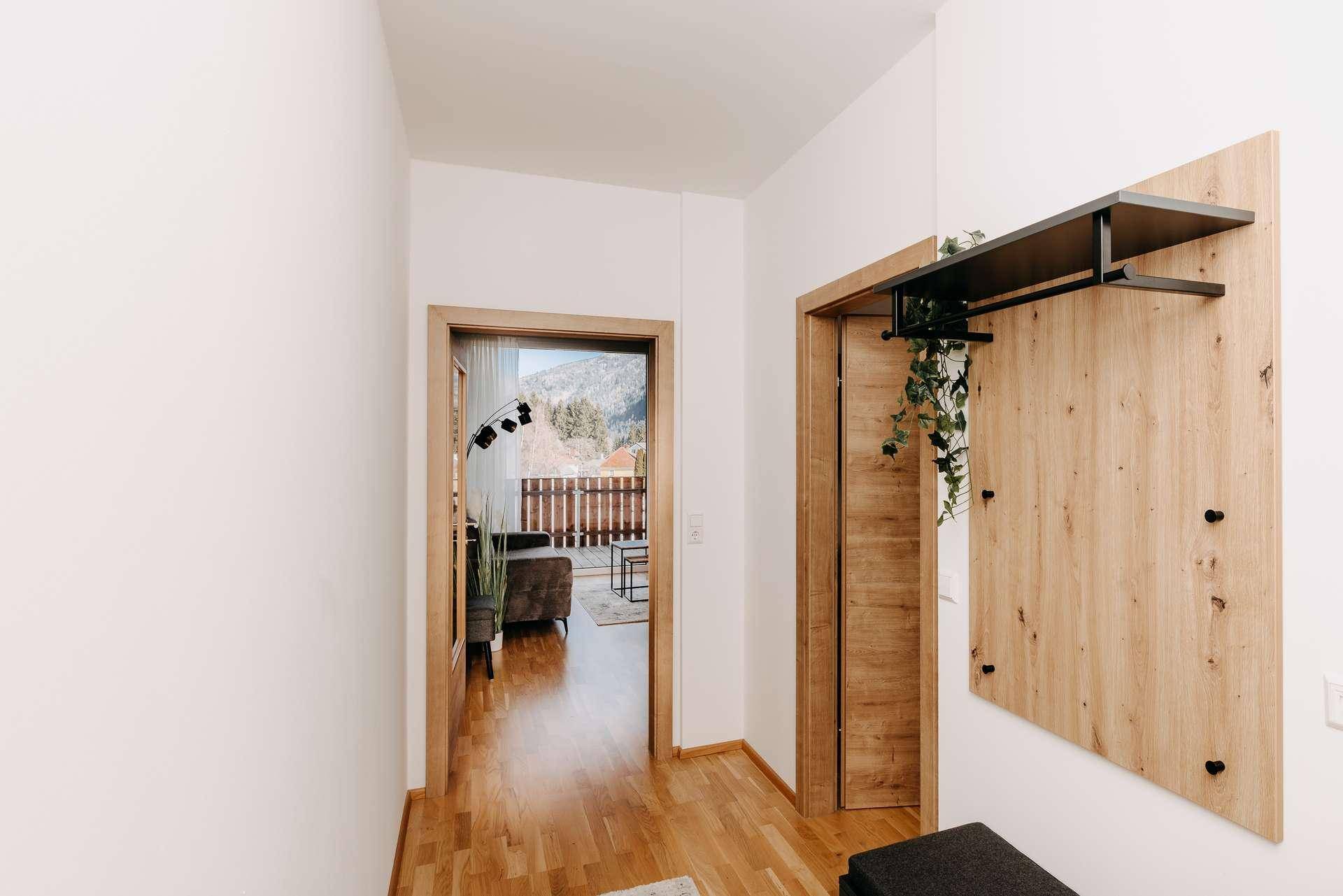 Heller Flur mit Holzboden und Garderobe, der zum Wohnbereich und Balkon führt.