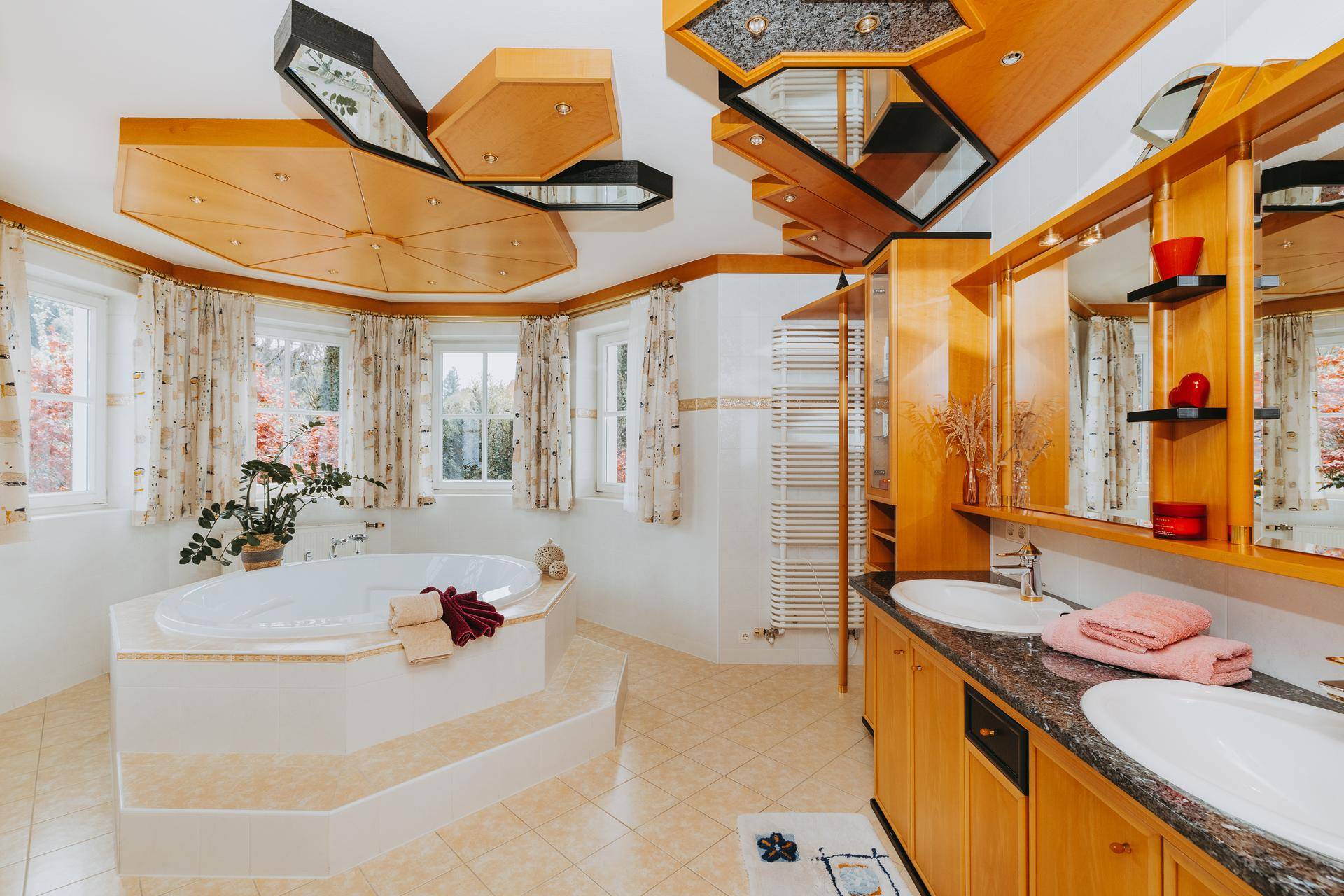Luxuriöses Badezimmer mit Doppelwaschbecken, Eckbadewanne und dekorativer Holzdecke.