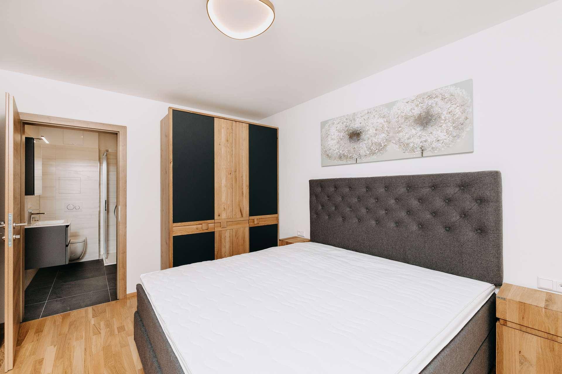 Schlafzimmer mit Doppelbett, modernem Kleiderschrank und Zugang zu einem Badezimmer.