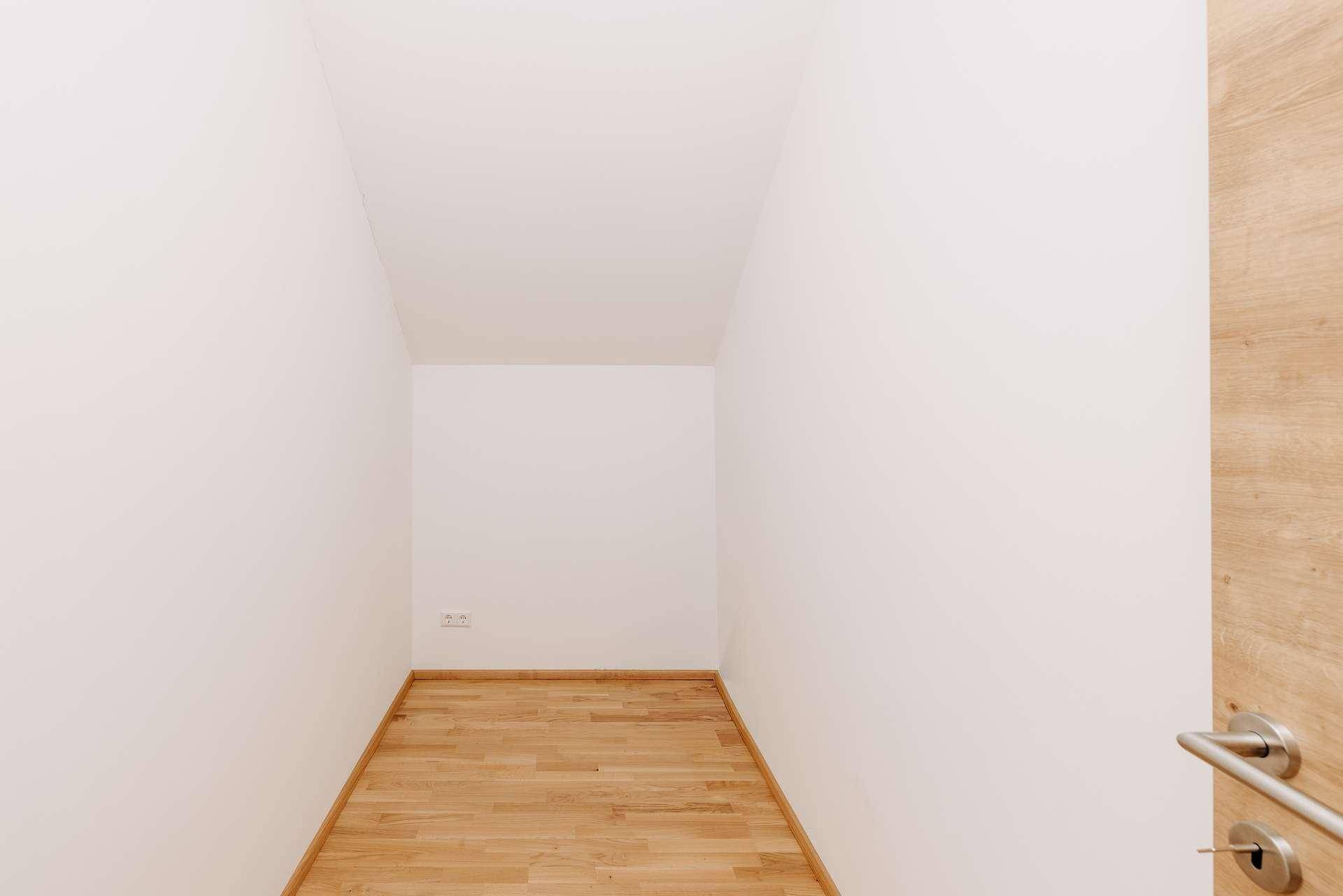 Leerer Abstellraum mit hellen Wänden und Holzboden, ideal für zusätzlichen Stauraum.