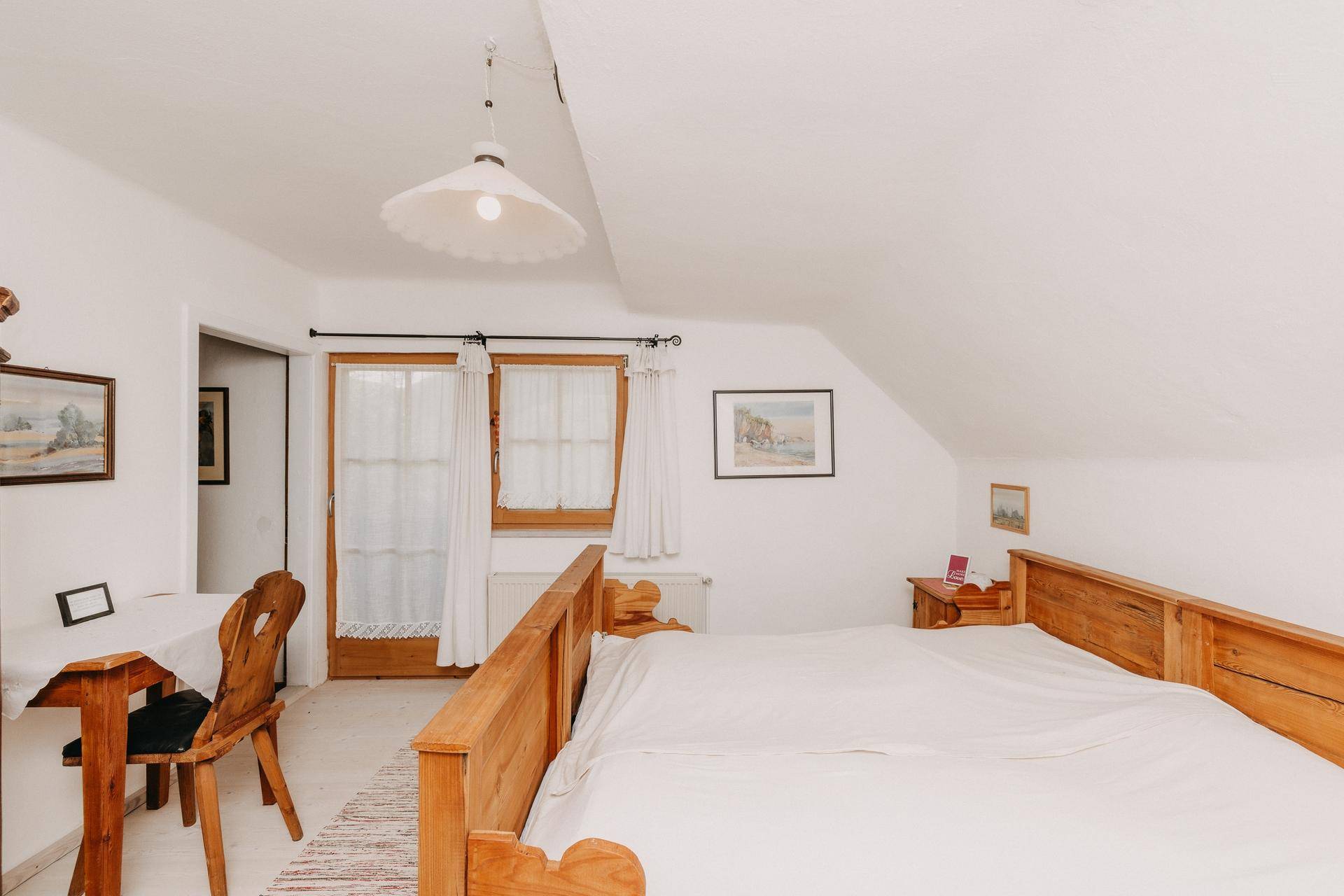 Schlafzimmer mit Holzbetten, Holzboden und Dachschräge, hell und freundlich.