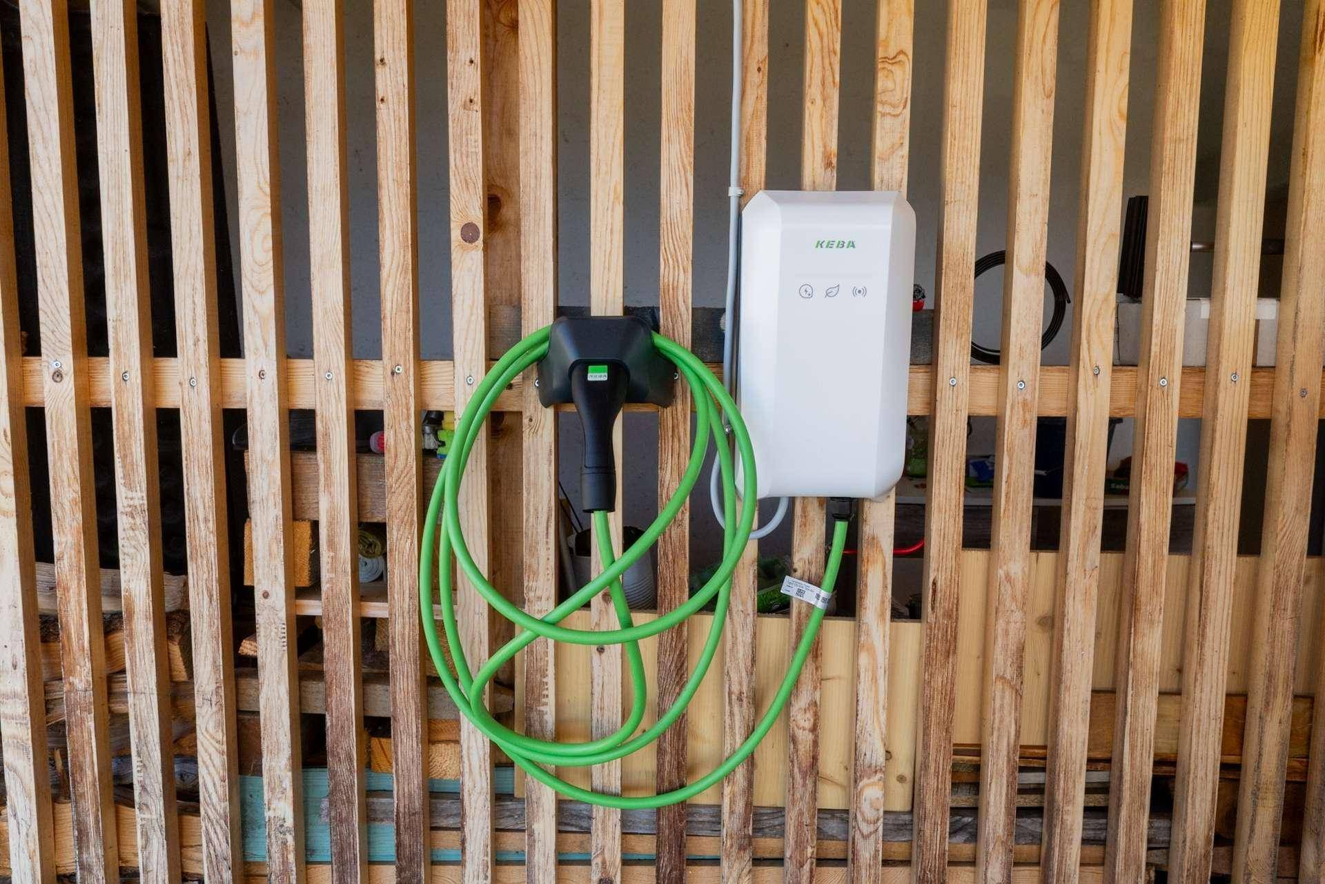 Ladestation für Elektrofahrzeuge an einer Holzverkleidung im Außenbereich.