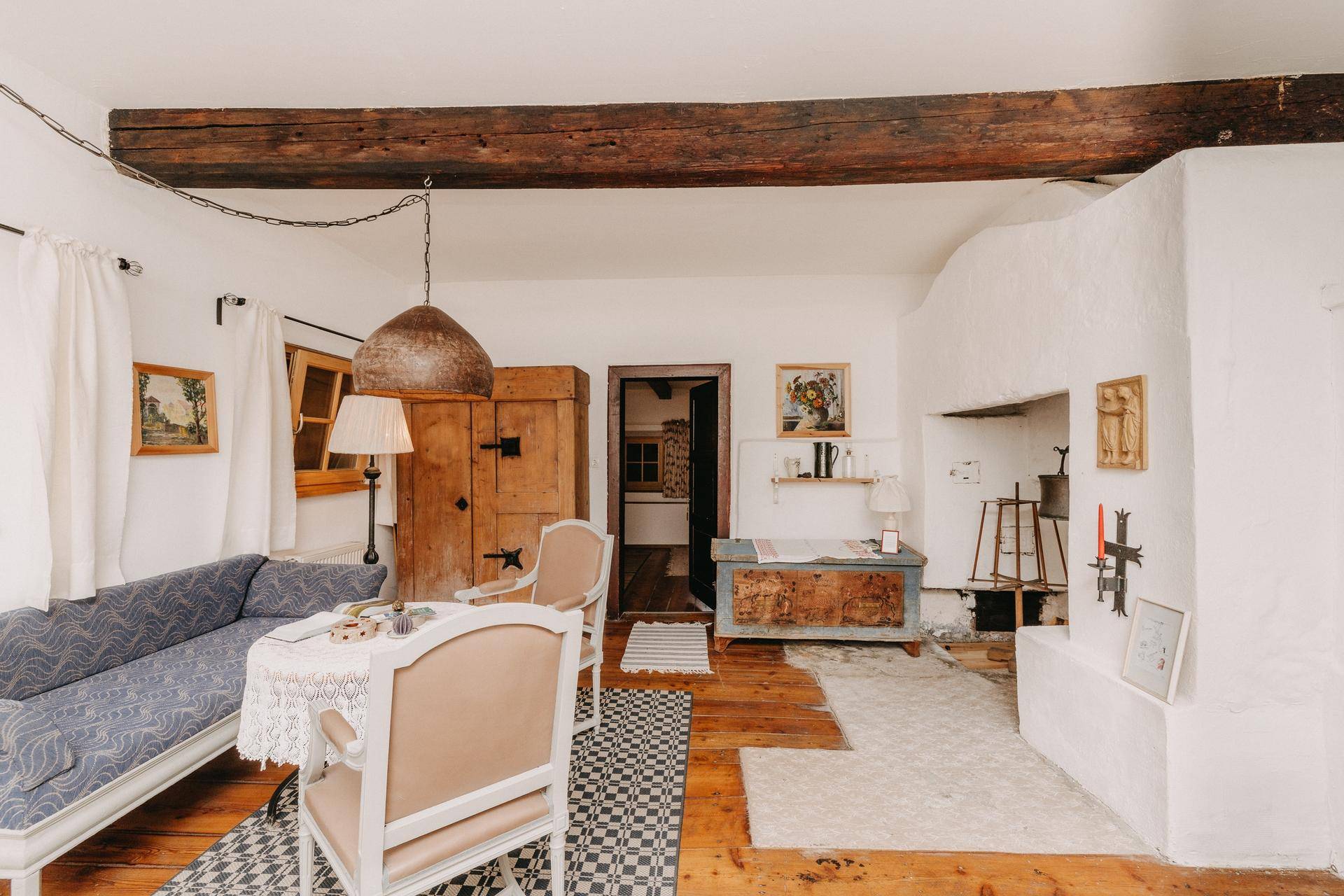 Rustikales Wohnzimmer mit Holzbalken, Kamin und traditionellen Möbeln.