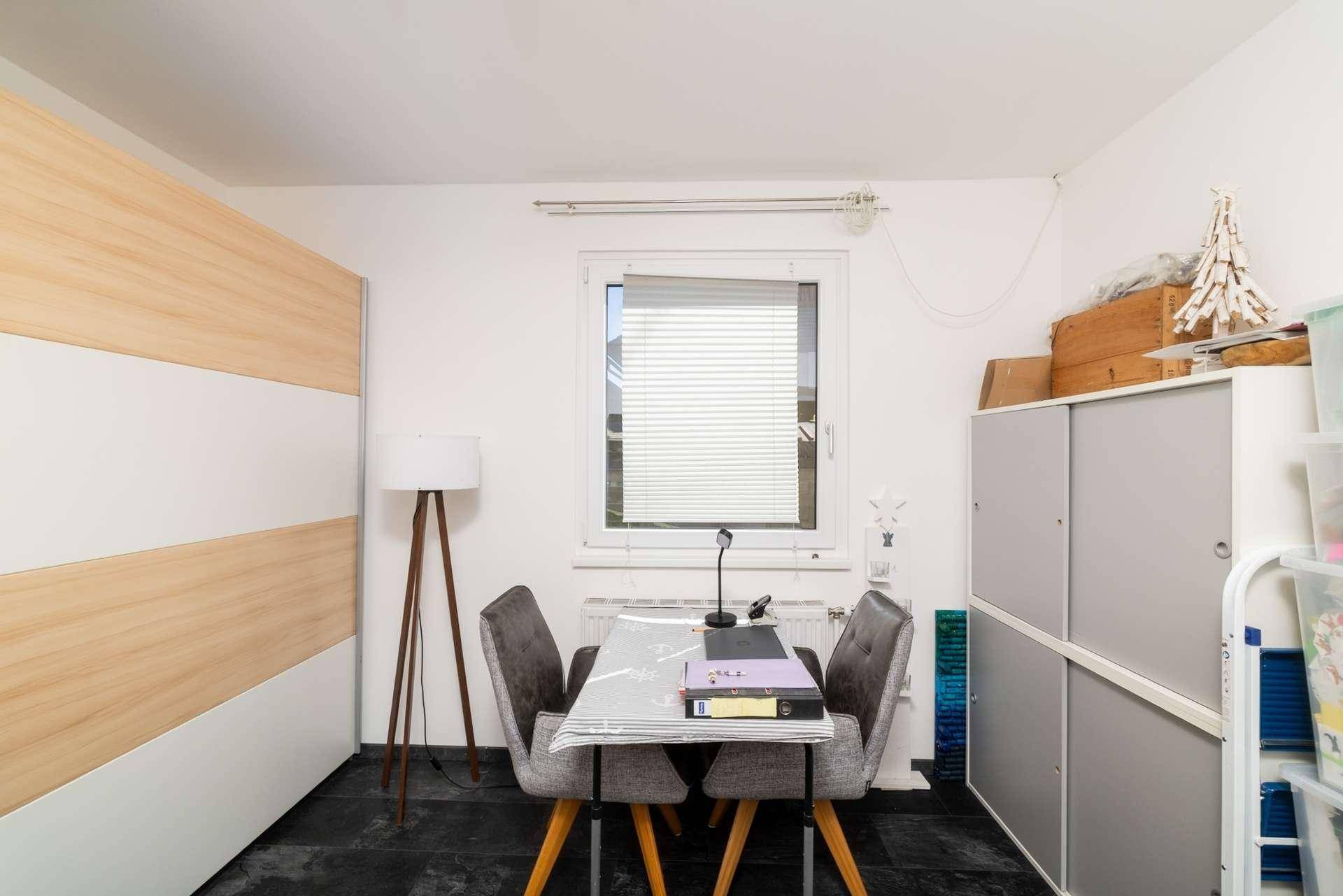Funktionaler Arbeitsbereich mit Schreibtisch, Stühlen und praktischen Aufbewahrungsmöbeln.