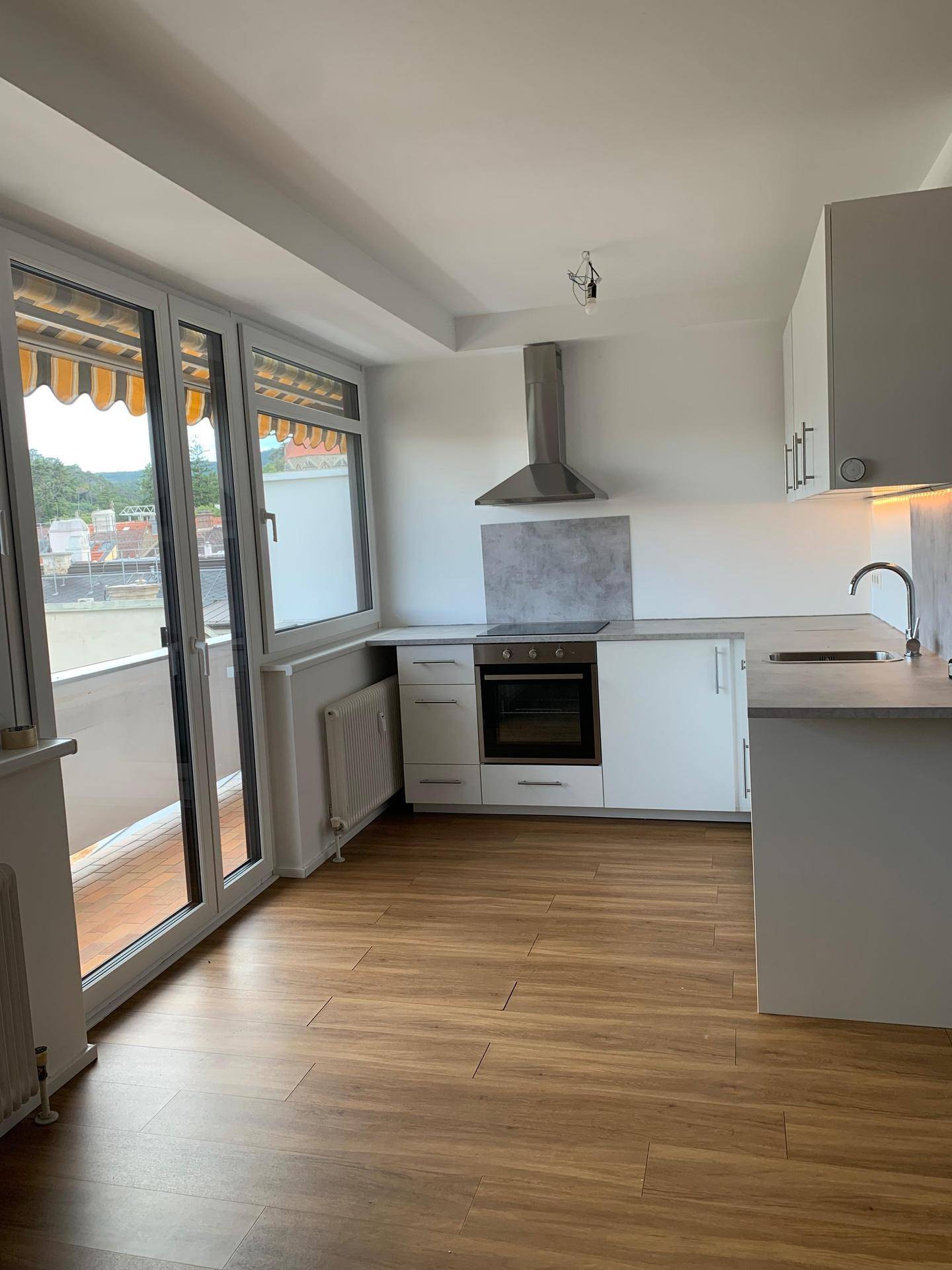 Moderne Küche mit weißen Schränken, Einbauherd und Zugang zum Balkon.