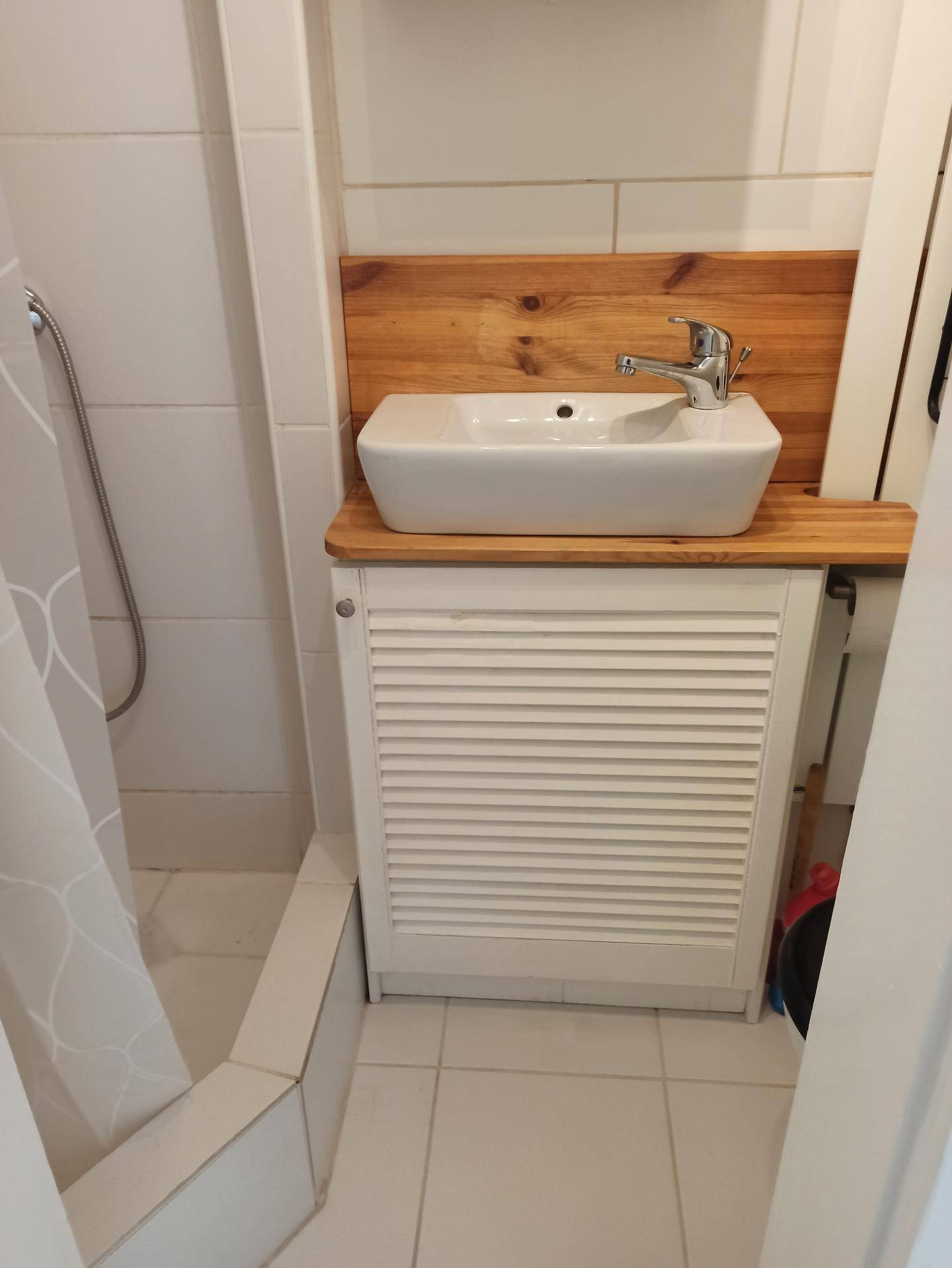 Modernes Badezimmer mit Aufsatzwaschbecken, Holzplatte und Duschbereich.