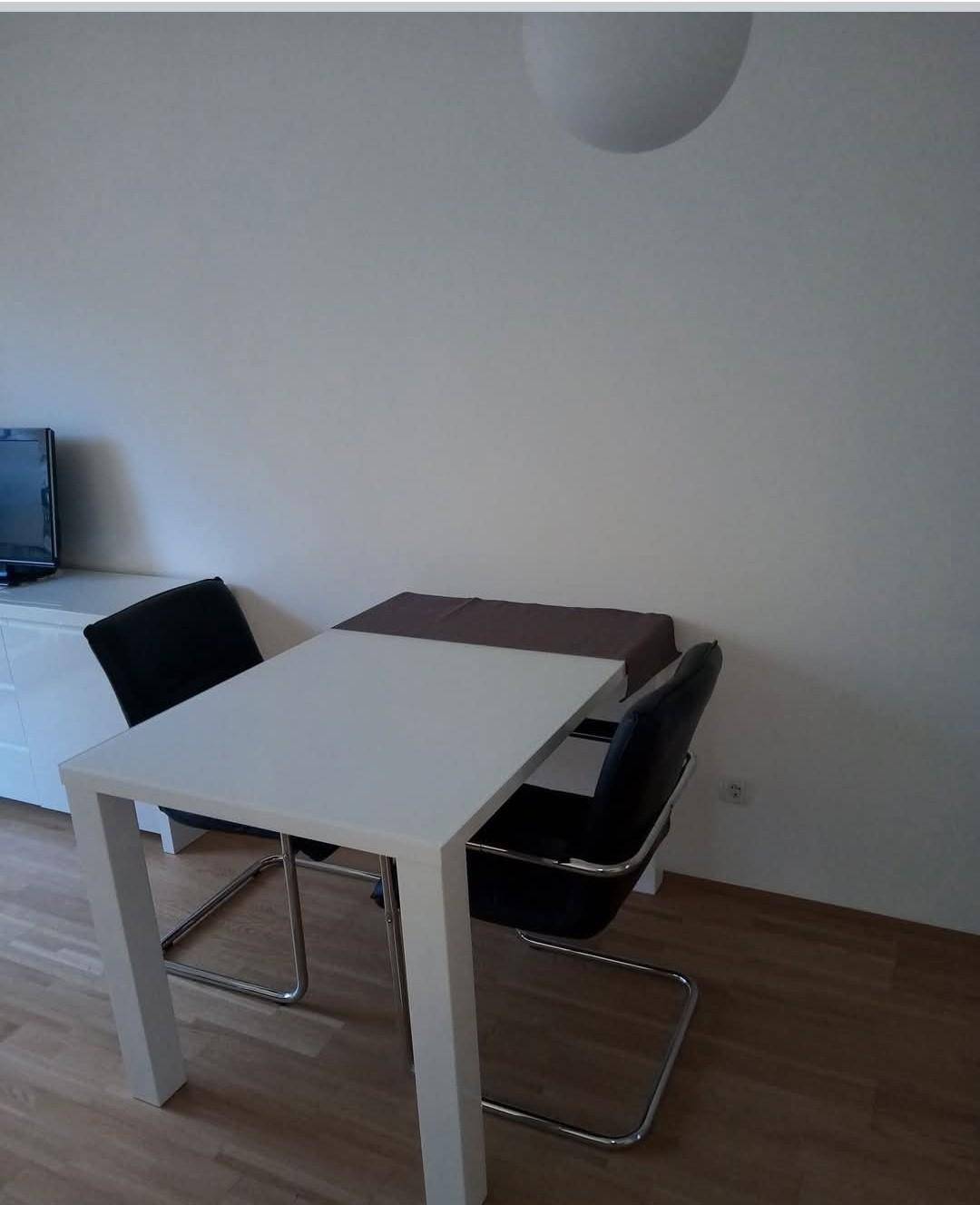Heller Essbereich mit modernem Esstisch, zwei Stühlen und Holzfußboden.