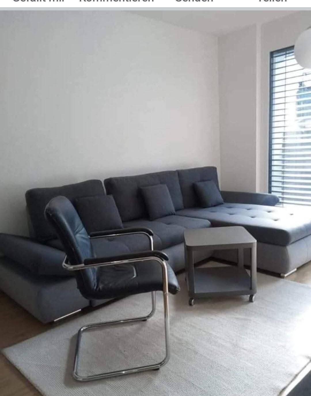Gemütliches Wohnzimmer mit großem Ecksofa, Beistelltisch und hellem Teppichboden.