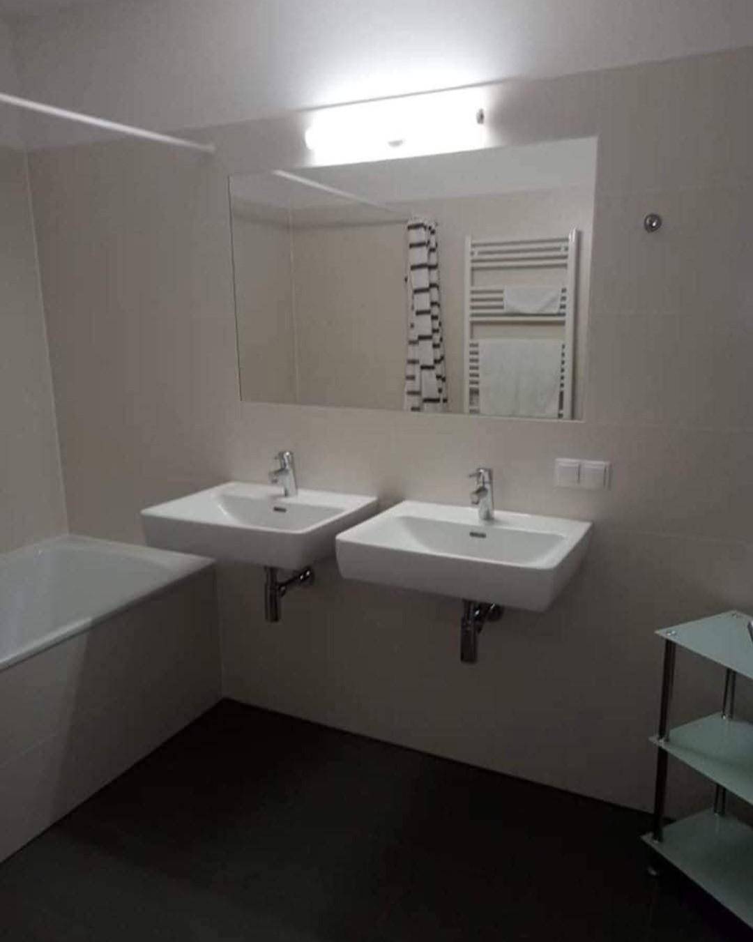 Modernes Badezimmer mit Doppelwaschbecken, Badewanne und großem Spiegel.