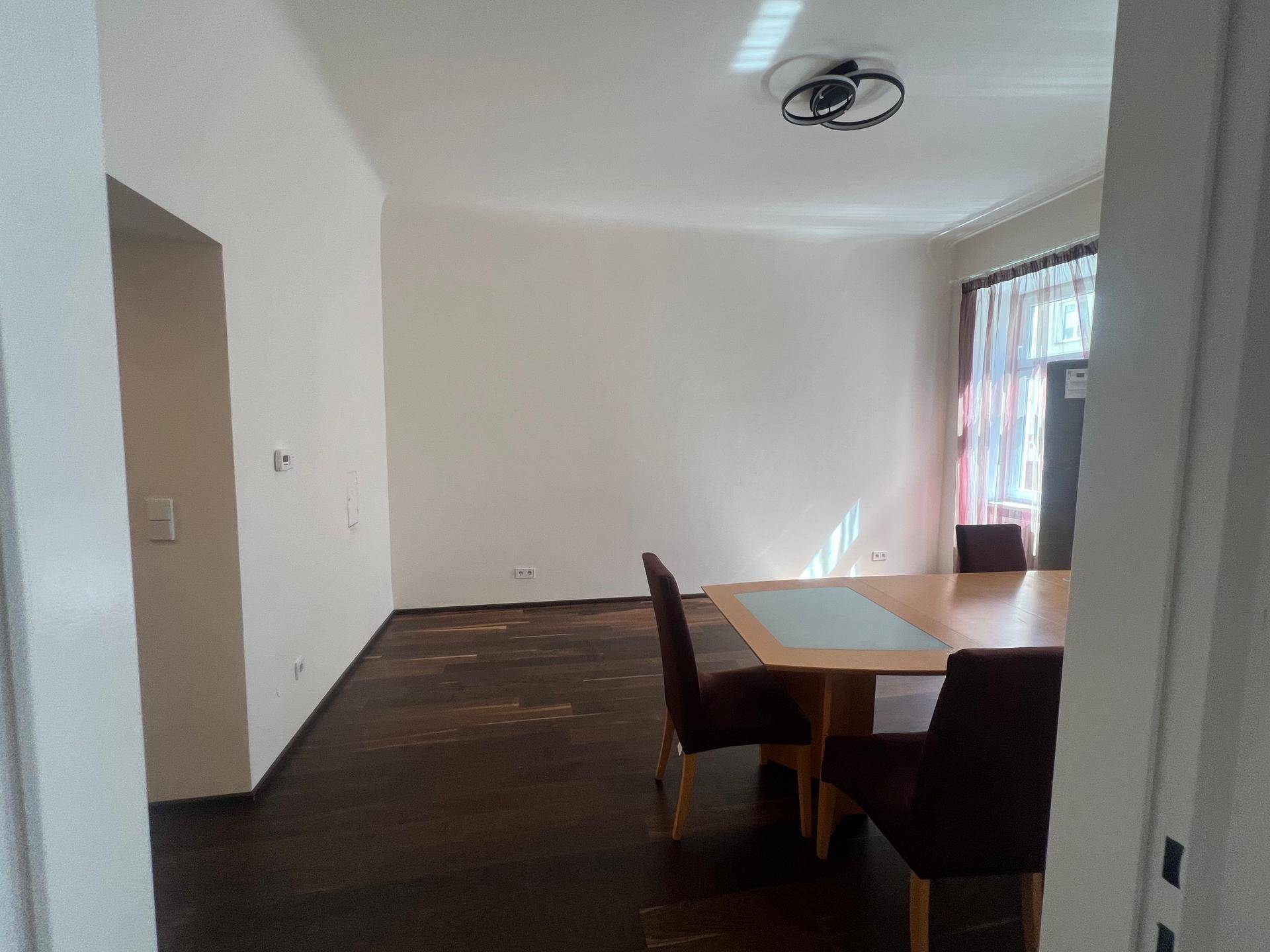 Essbereich mit dunklem Holzboden und einem großen Esstisch, der auf weitere Räume blicken lässt.
