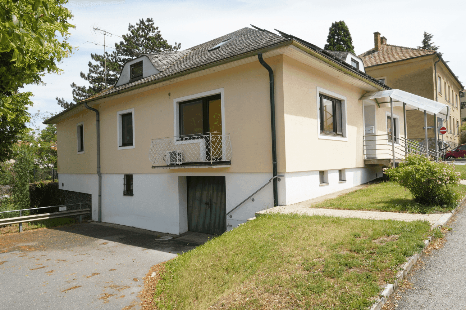 Rückansicht des Hauses mit kleinem Balkon und Garagenzufahrt im Untergeschoss.