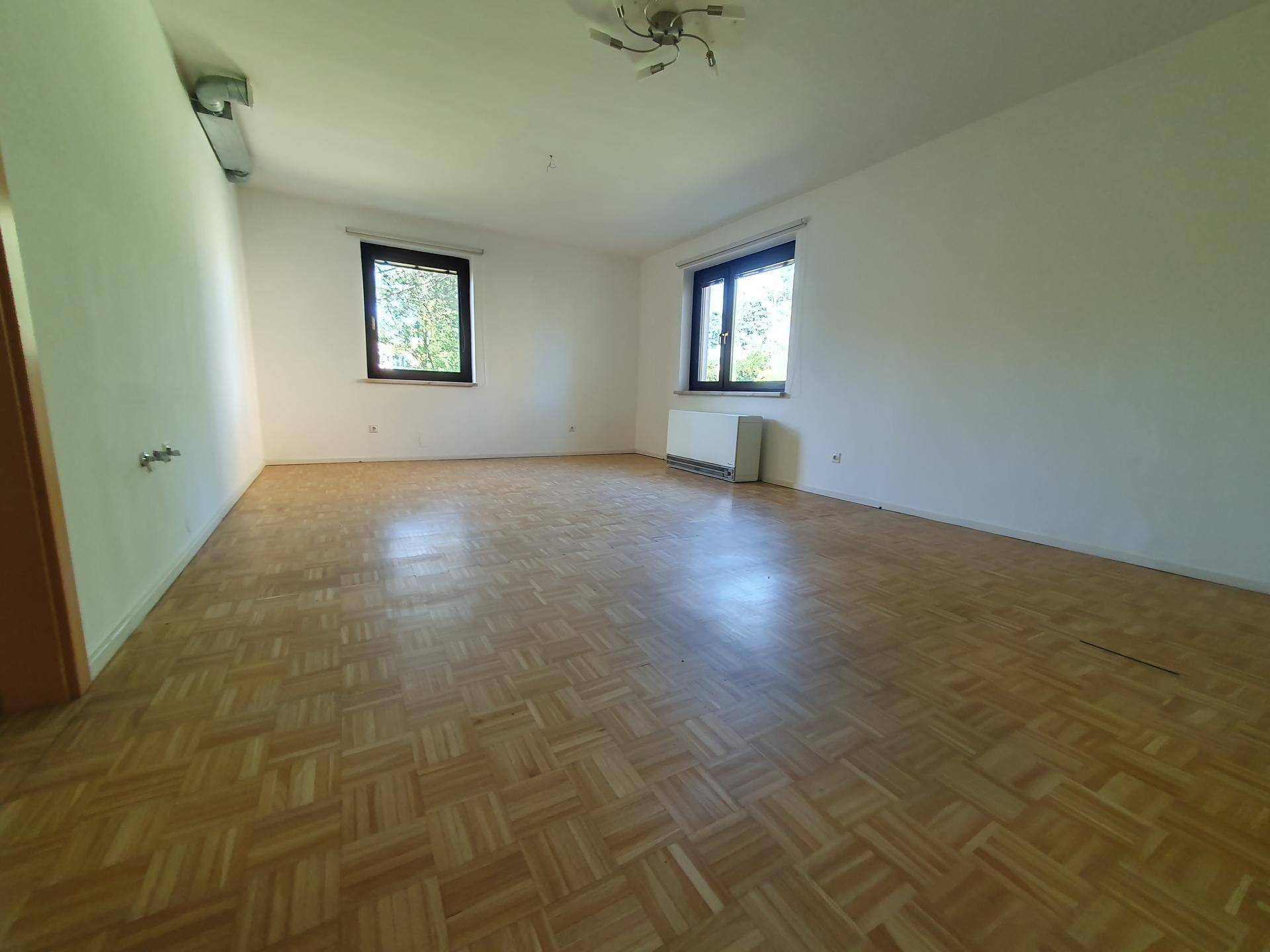 Helles Zimmer mit Fischgrätparkett und weißen Wänden, bereit zur individuellen Gestaltung.