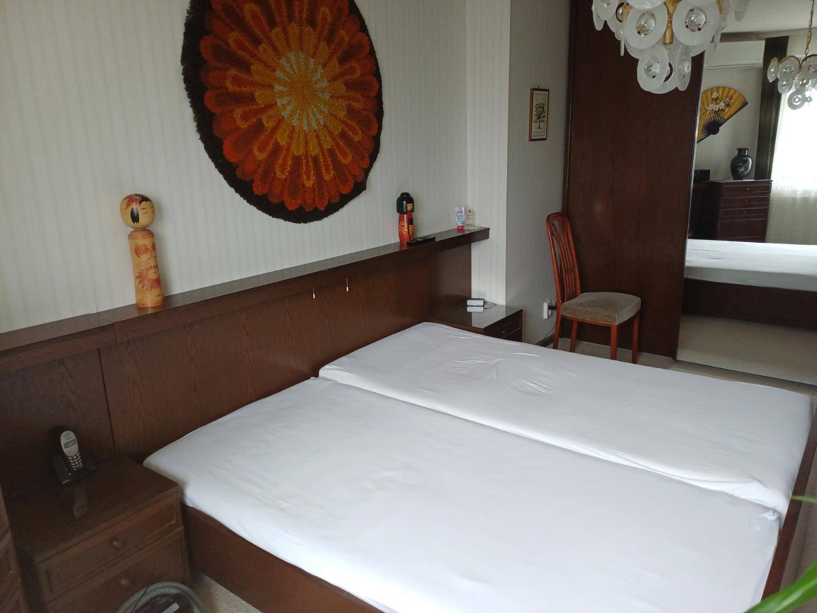 Schlafzimmer mit Doppelbett, Nachttischen und dekorativem Wandteppich.