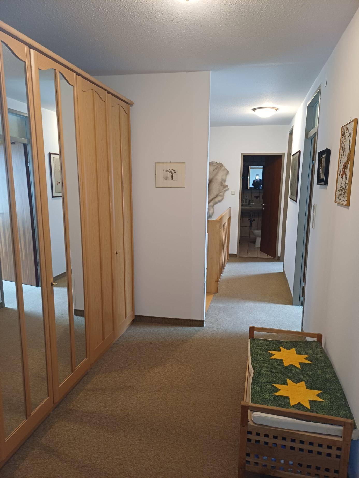 Heller Flur mit Spiegelschränken und Teppichboden, führt zu weiteren Räumen.