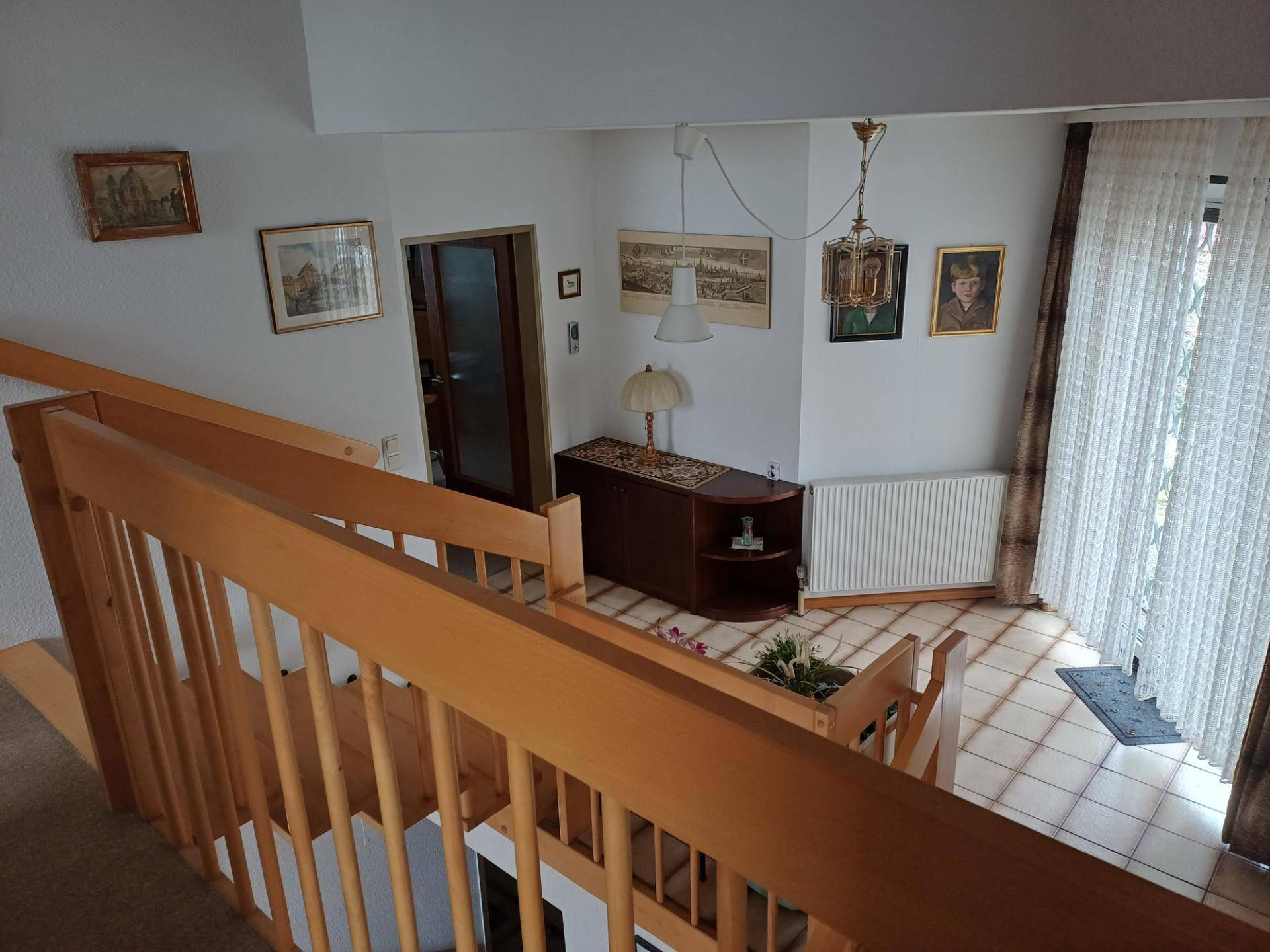 Holztreppe führt in einen unteren Bereich mit Fliesenboden und Heizkörper.