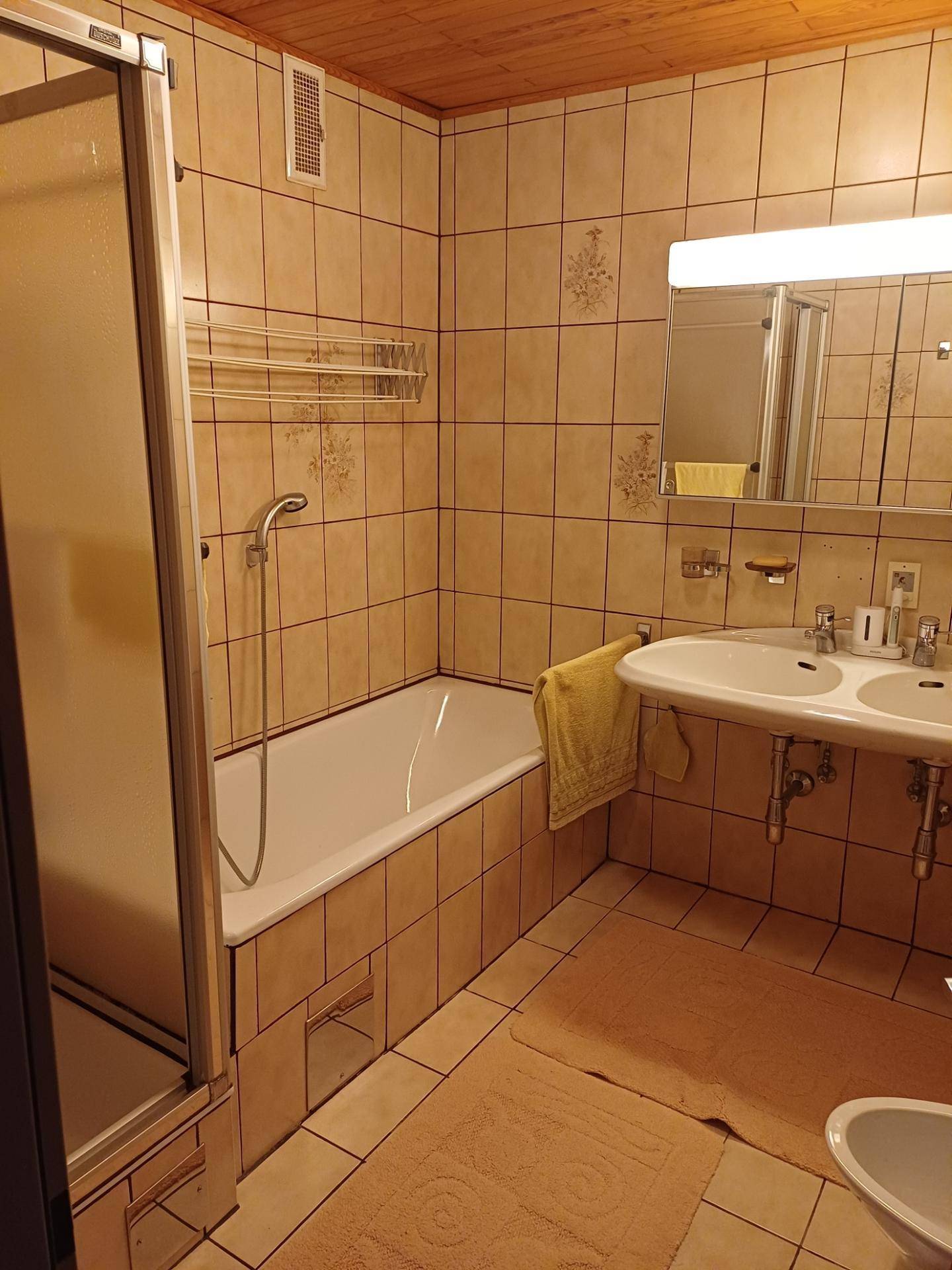 Gefliestes Badezimmer mit Badewanne, Duschkabine und Doppelwaschbecken.